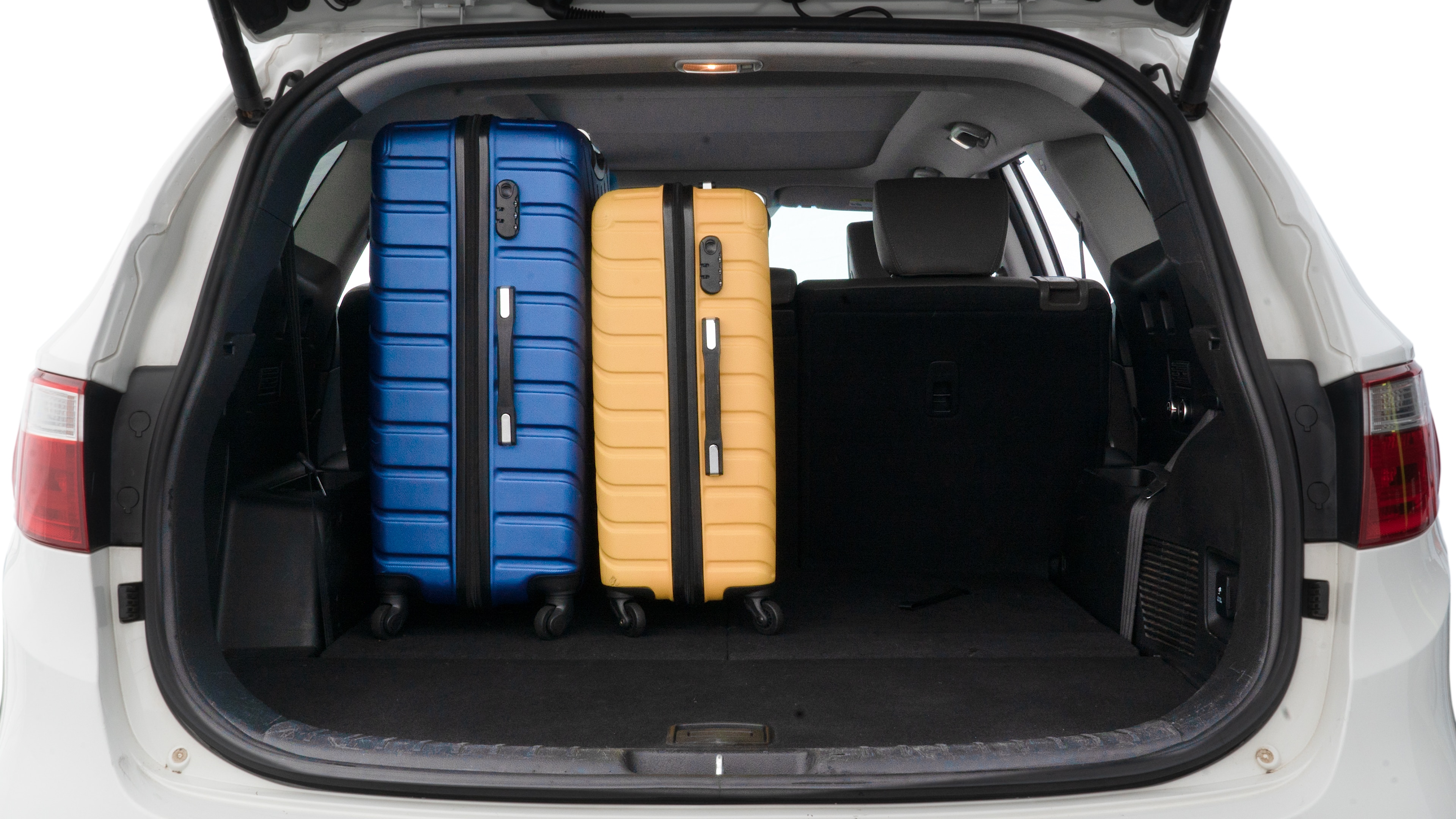 The trunk lid is open, showing full view of the trunk space. One large, two medium, and two small suitcases are placed inside.