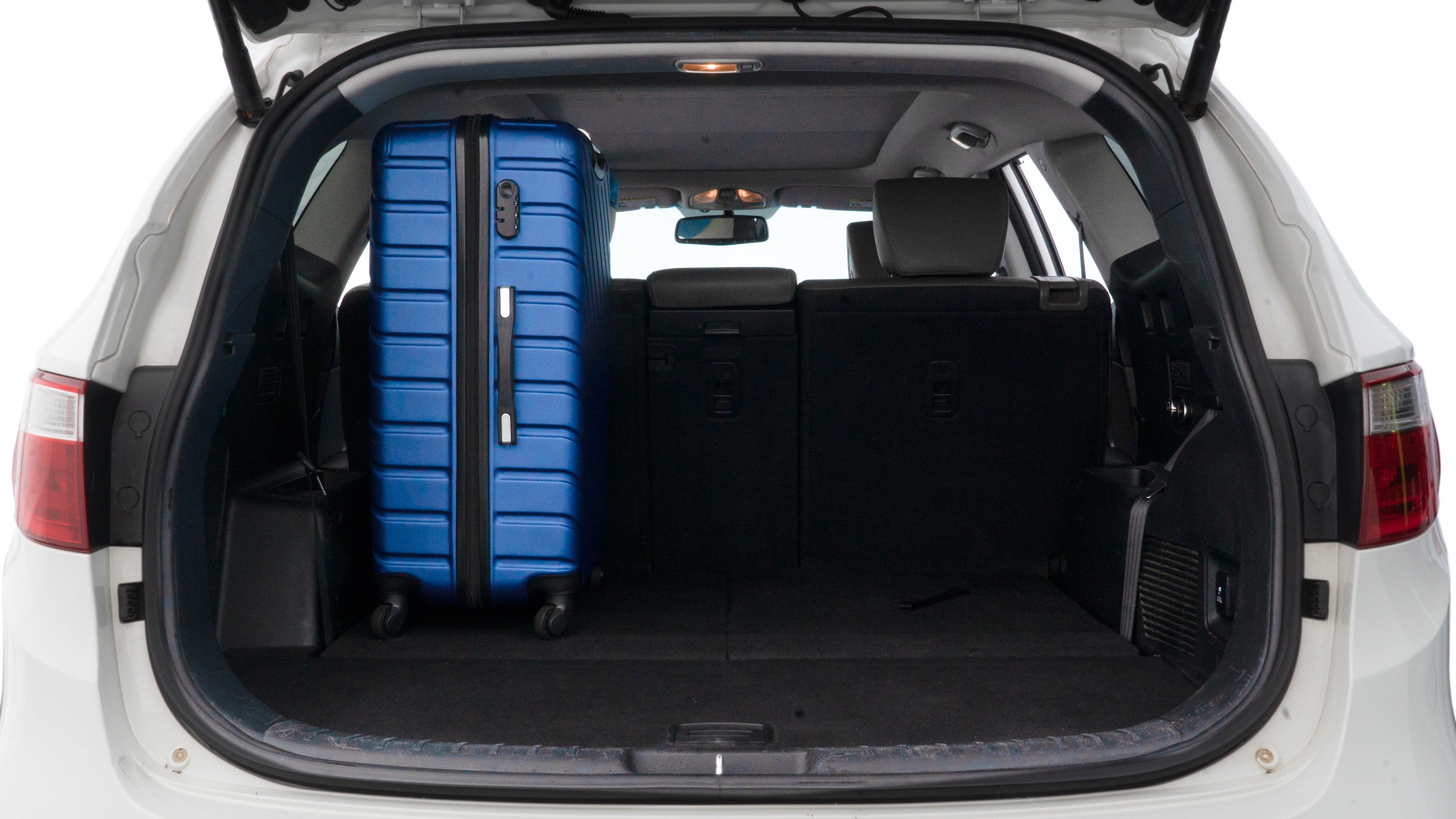 The trunk lid is open, showing full view of the trunk space. One large, two medium, and two small suitcases are placed inside.