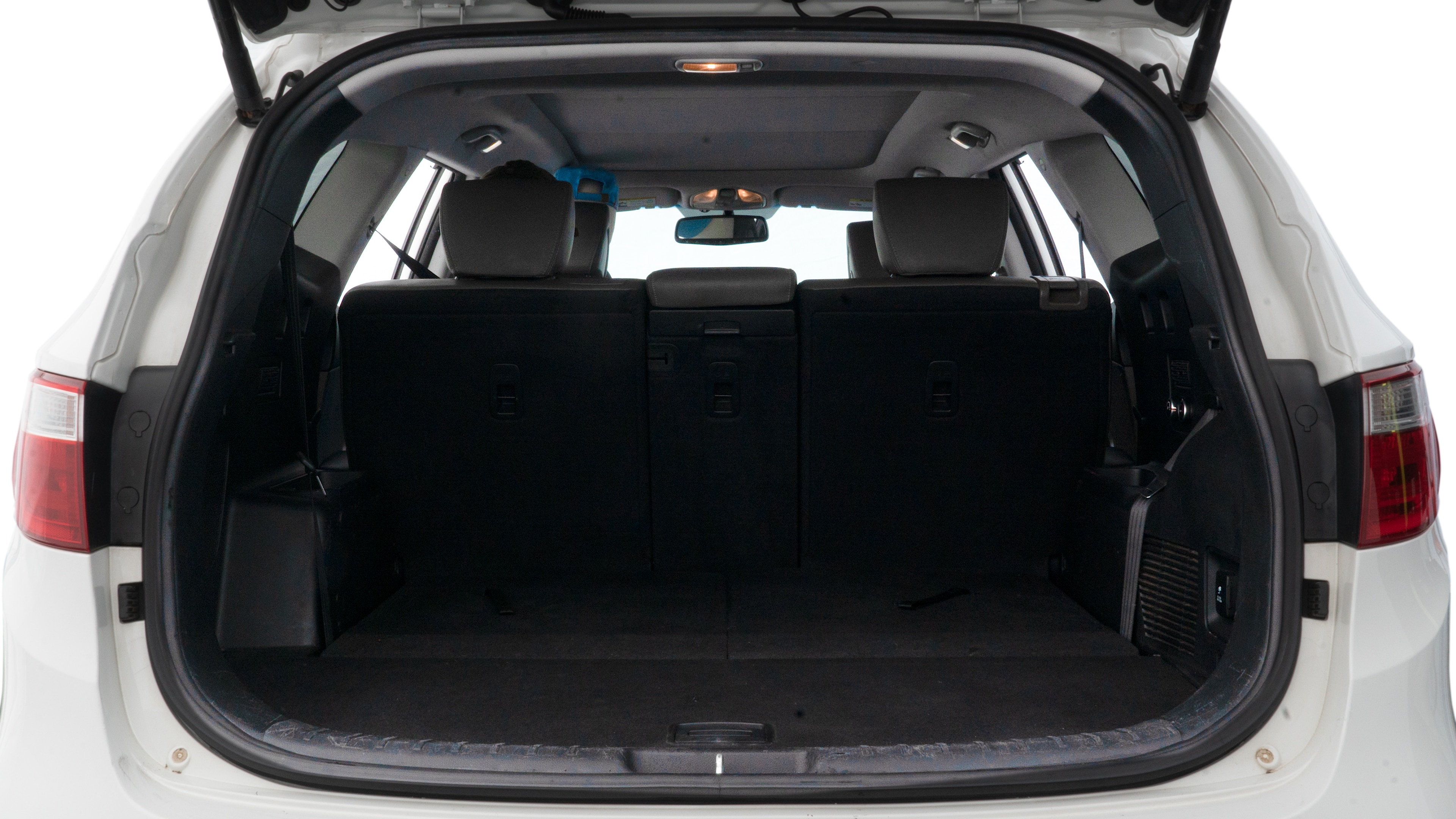 The trunk lid is open, showing full view of the trunk space. One large, two medium, and two small suitcases are placed inside.