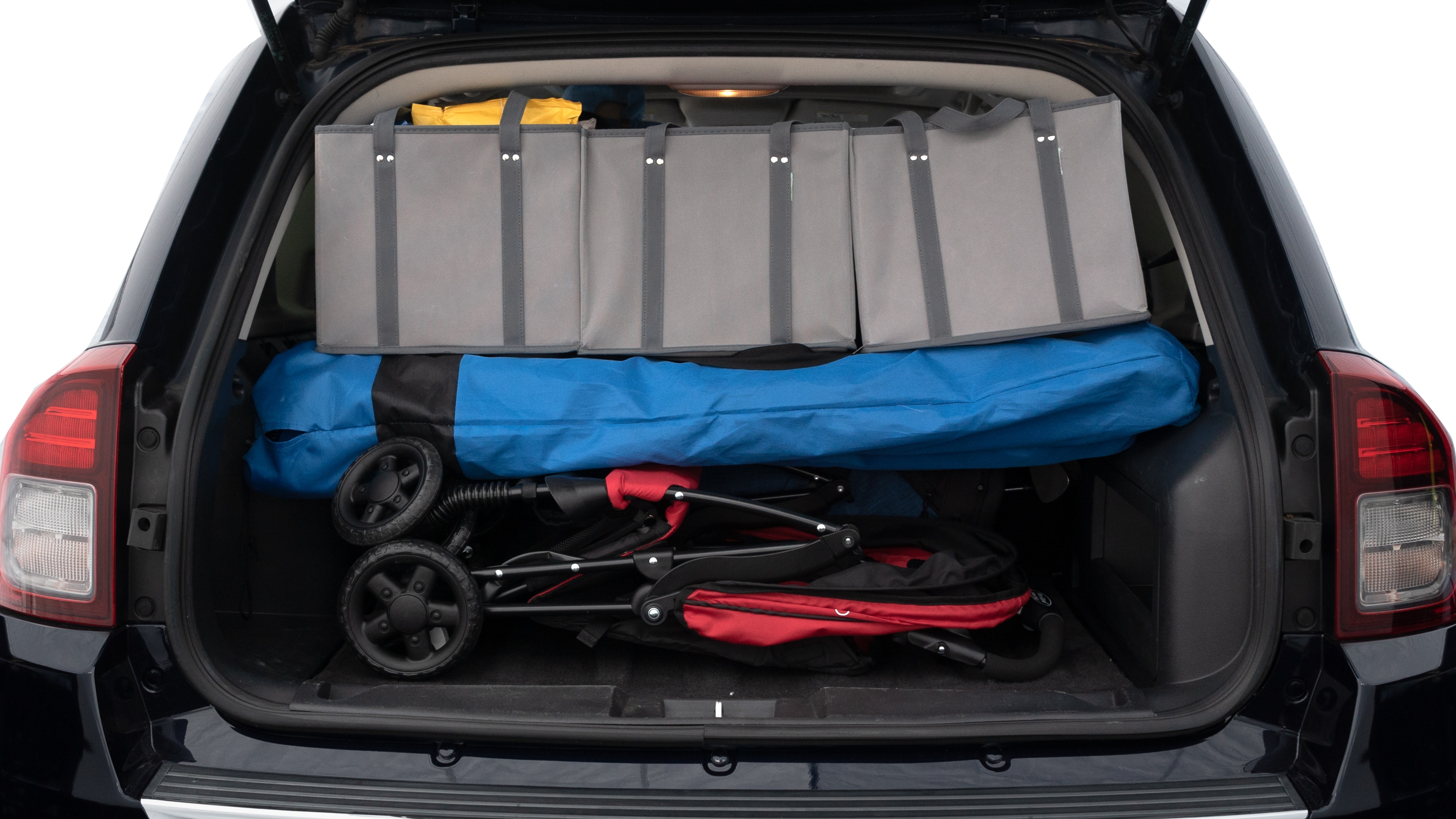 The trunk lid is open showing full view of the trunk. A baby stroller, three grocery carriers, two camping chairs in the carrying bag, and a set of golf clubs are placed inside.