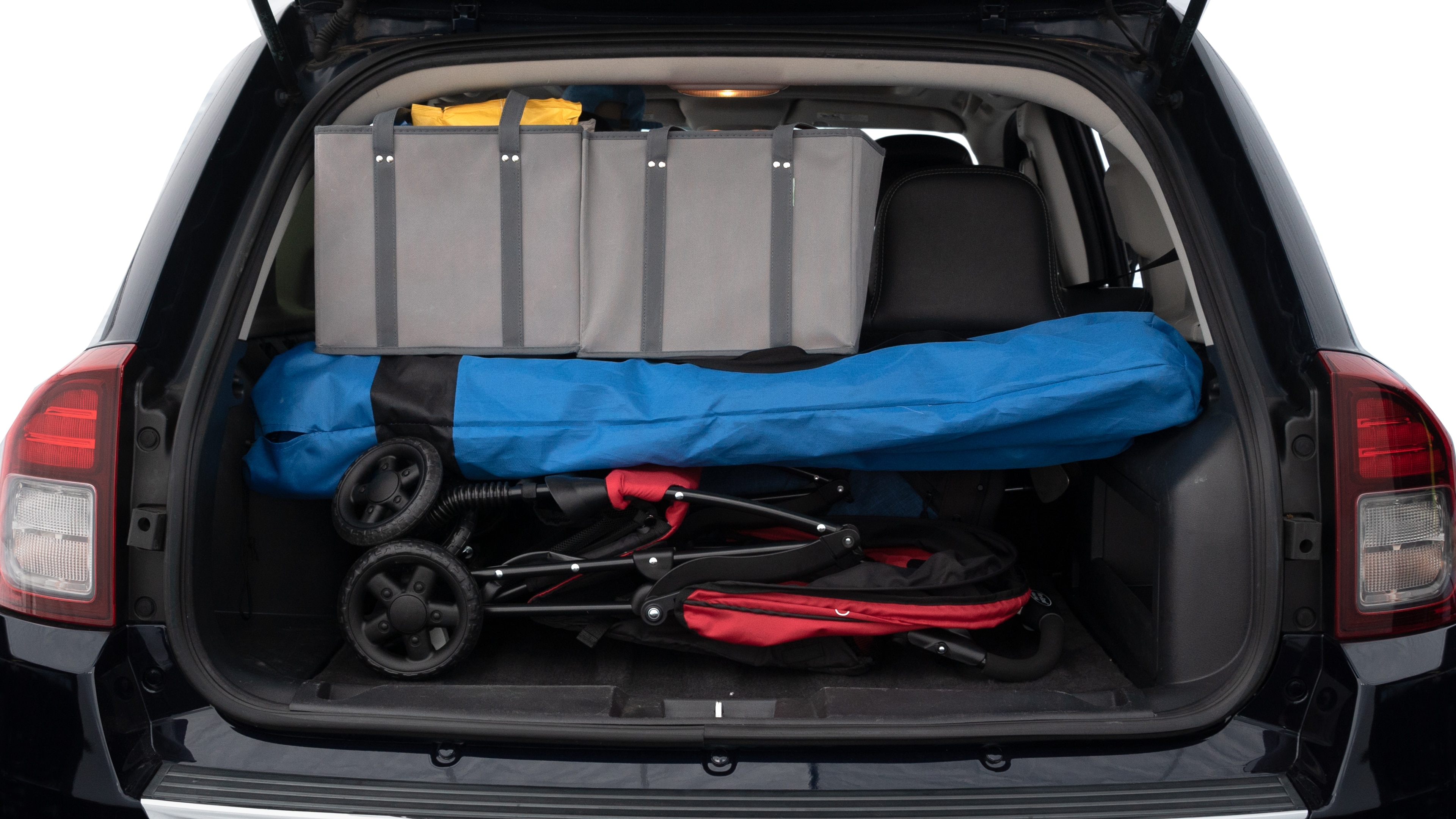 The trunk lid is open showing full view of the trunk. A baby stroller, three grocery carriers, two camping chairs in the carrying bag, and a set of golf clubs are placed inside.