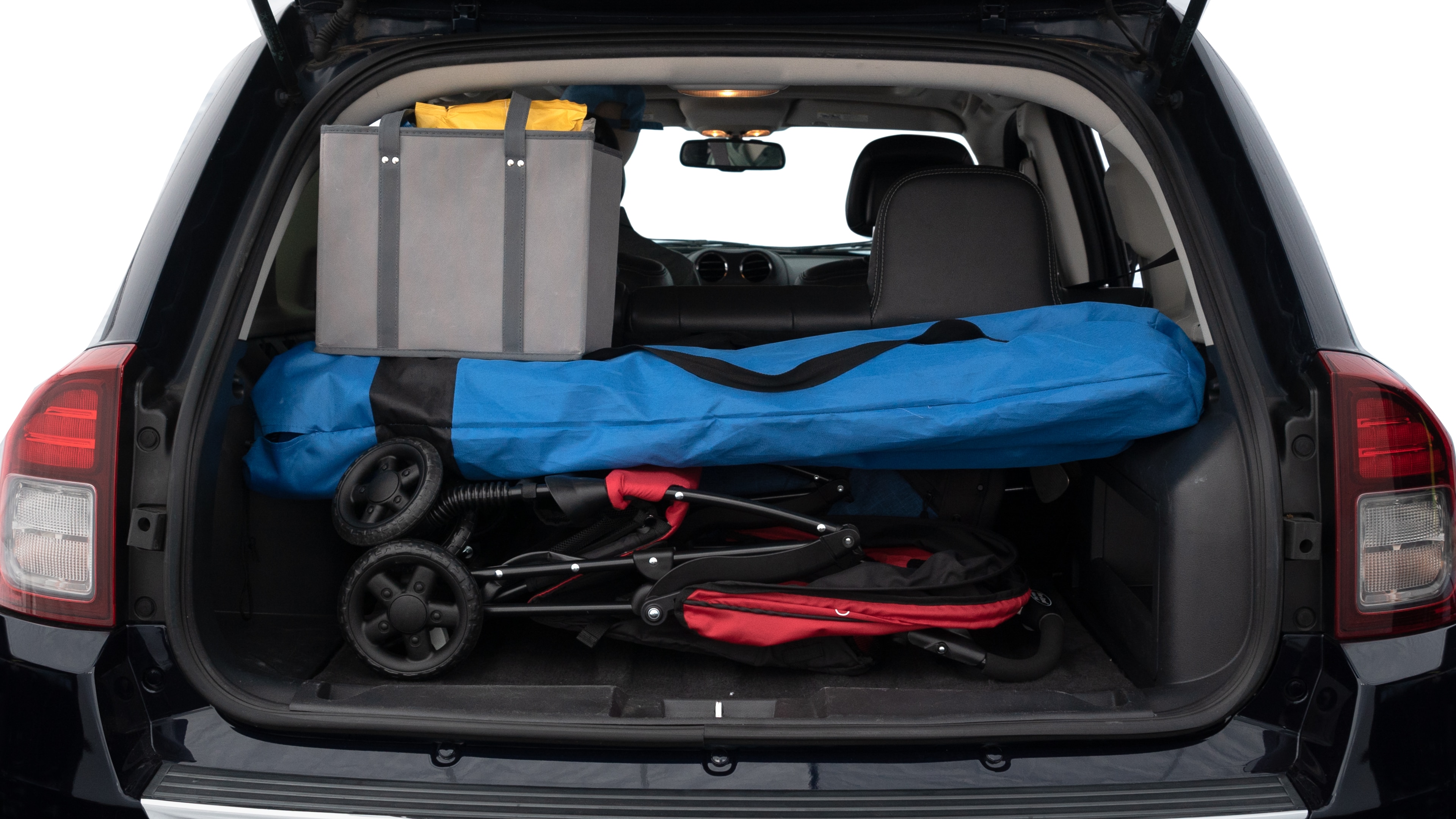 The trunk lid is open showing full view of the trunk. A baby stroller, three grocery carriers, two camping chairs in the carrying bag, and a set of golf clubs are placed inside.