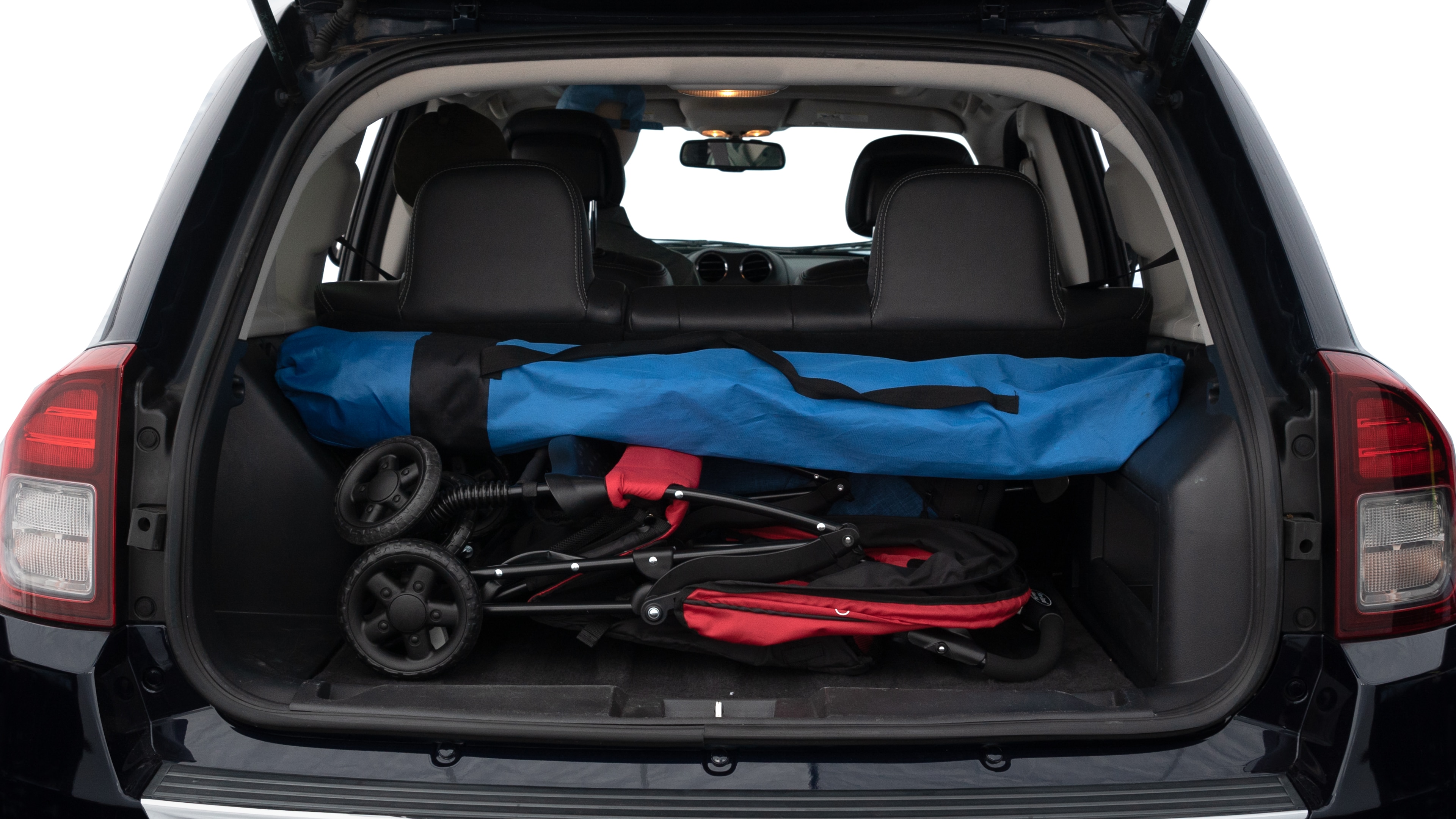 The trunk lid is open showing full view of the trunk. A baby stroller, three grocery carriers, two camping chairs in the carrying bag, and a set of golf clubs are placed inside.