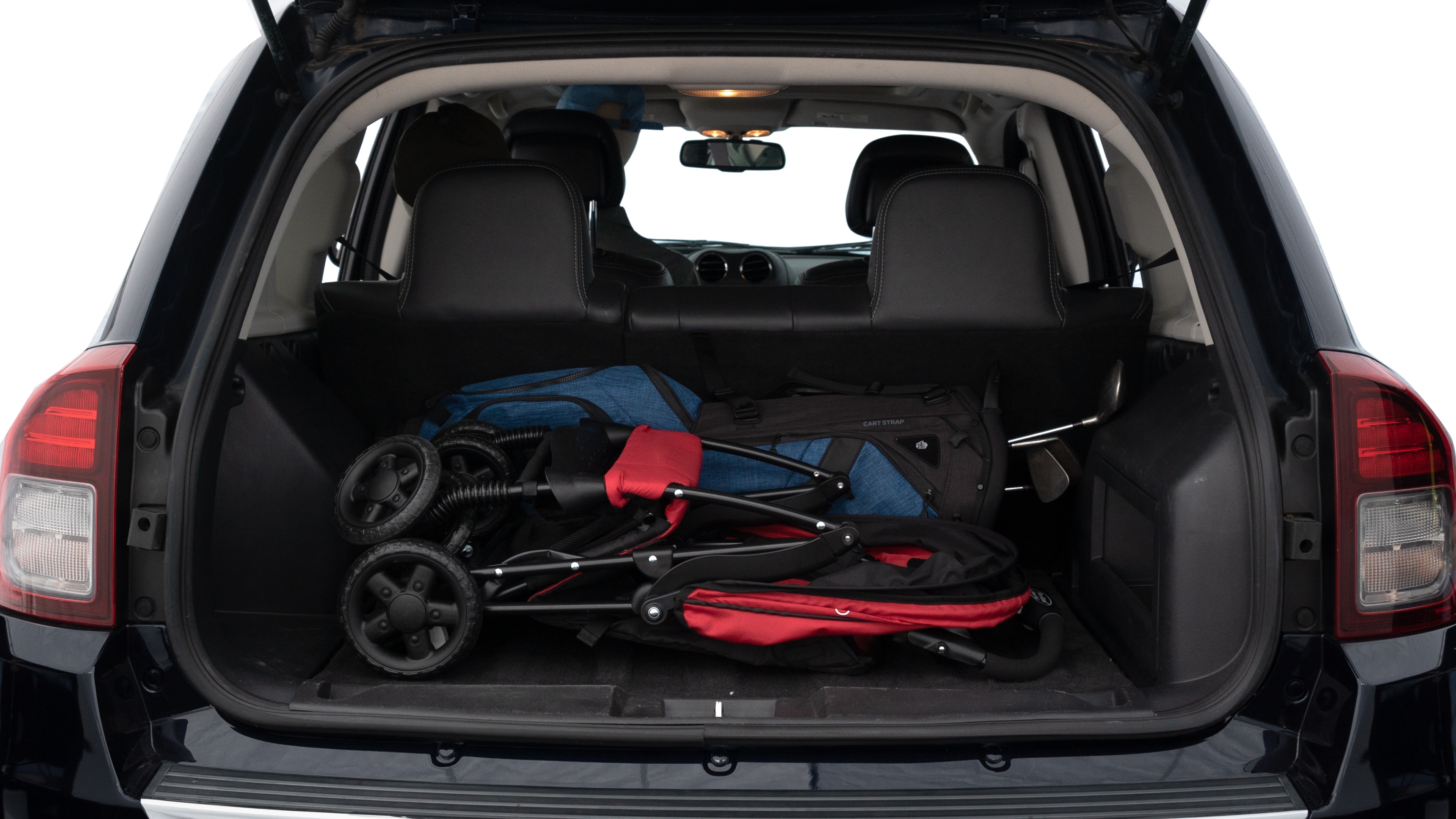 The trunk lid is open showing full view of the trunk. A baby stroller, three grocery carriers, two camping chairs in the carrying bag, and a set of golf clubs are placed inside.