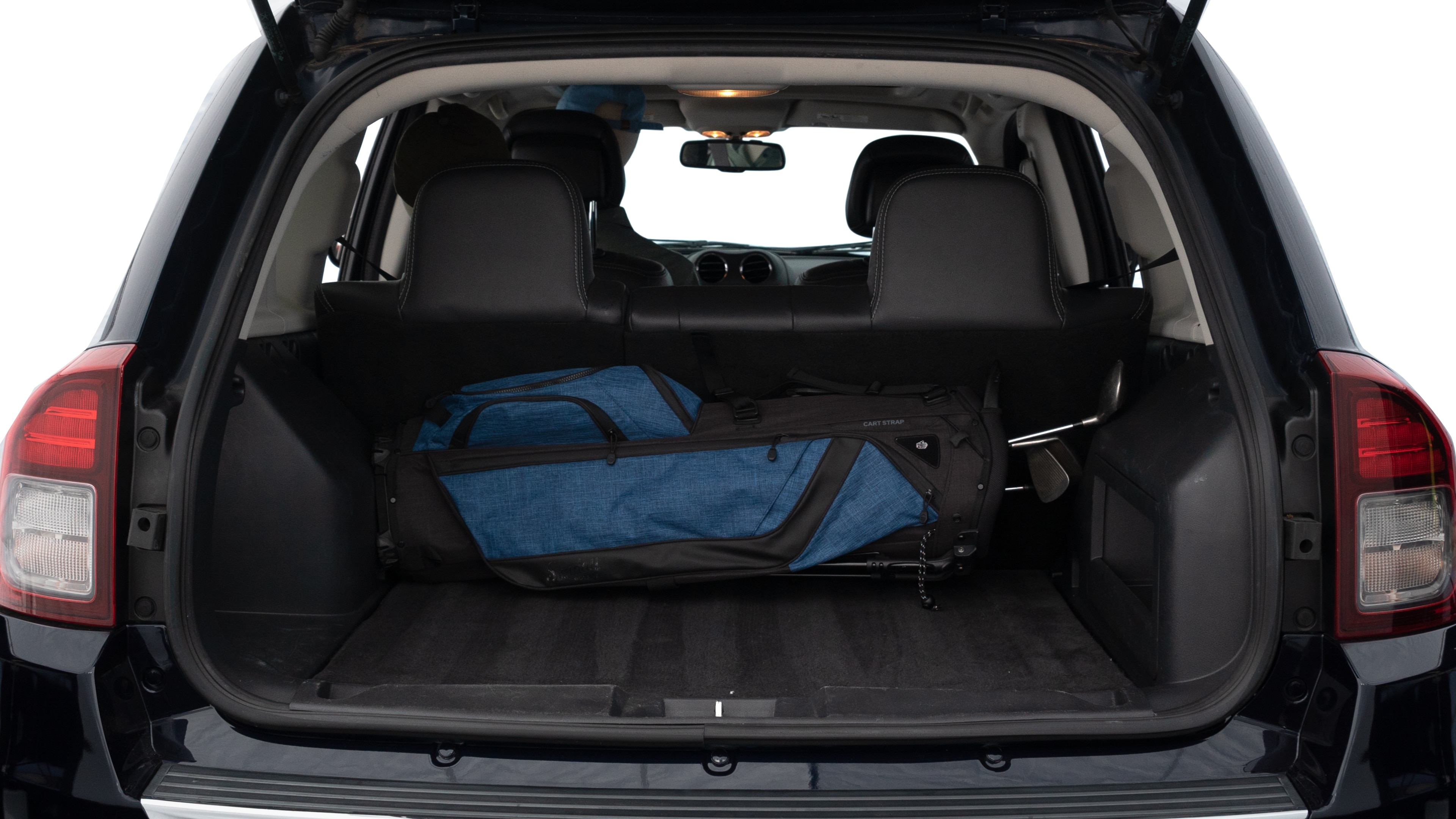 The trunk lid is open showing full view of the trunk. A baby stroller, three grocery carriers, two camping chairs in the carrying bag, and a set of golf clubs are placed inside.