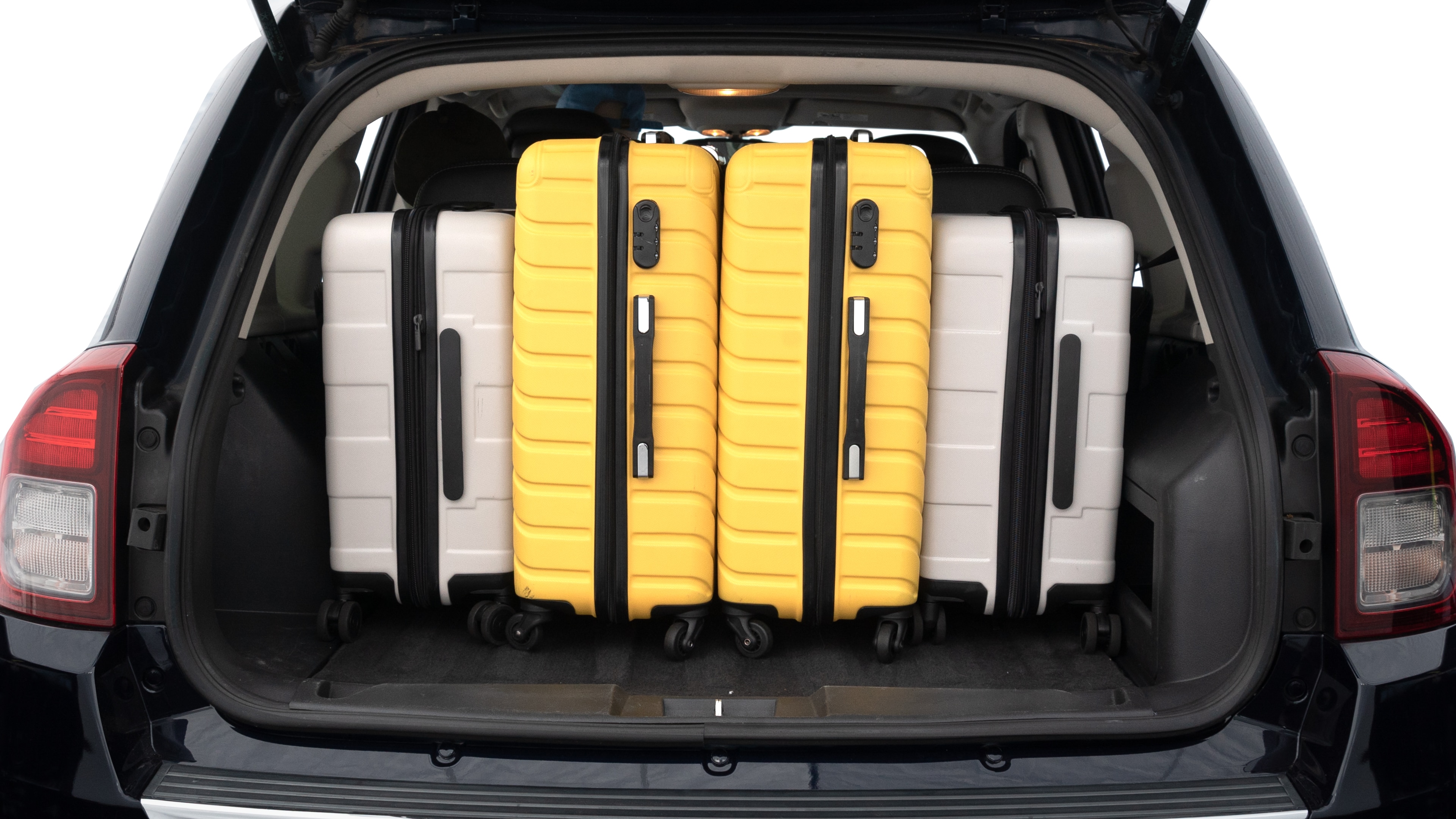 The trunk lid is open, showing full view of the trunk space. Two medium and two small suitcases are placed inside.