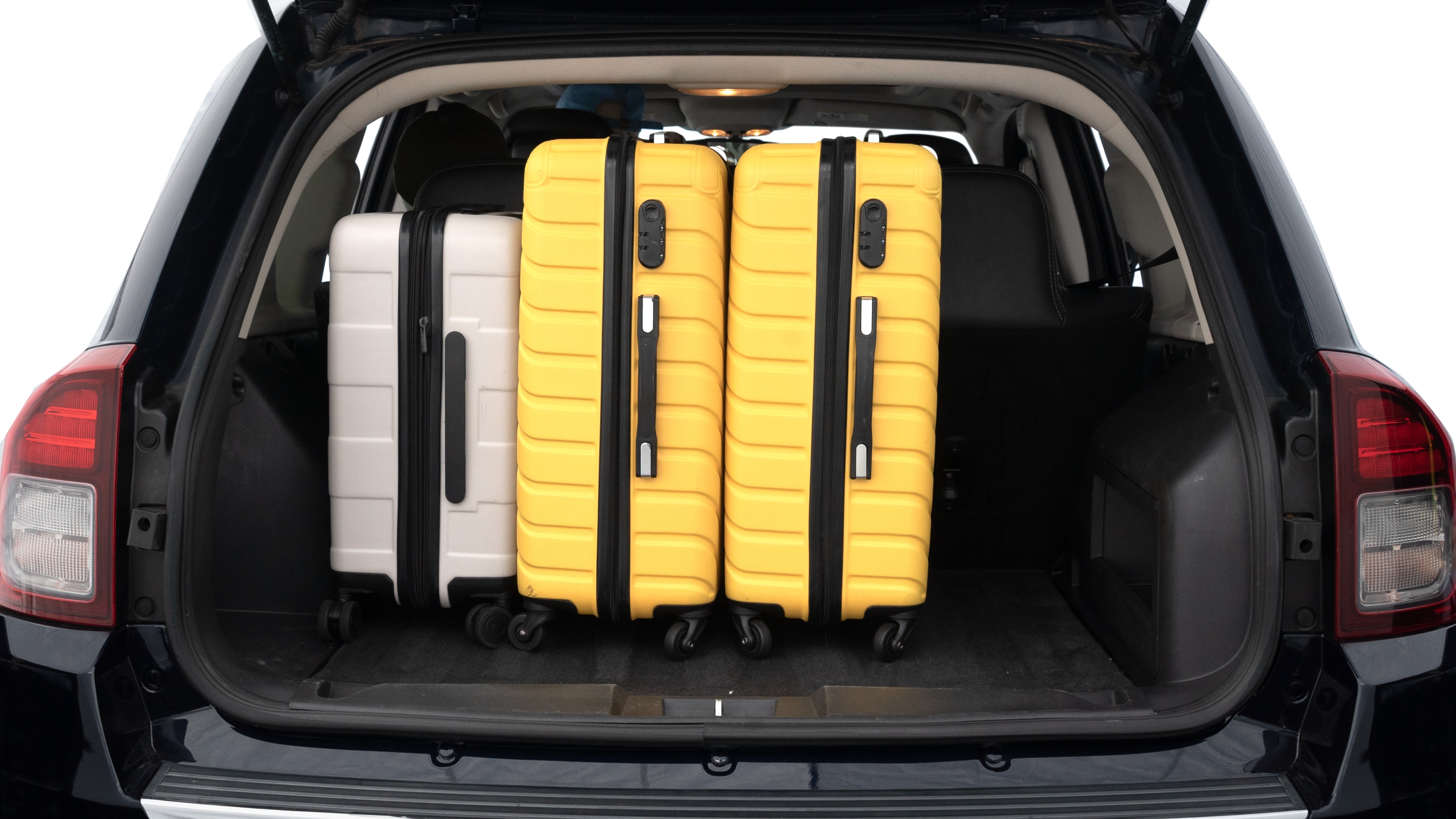 The trunk lid is open, showing full view of the trunk space. Two medium and two small suitcases are placed inside.