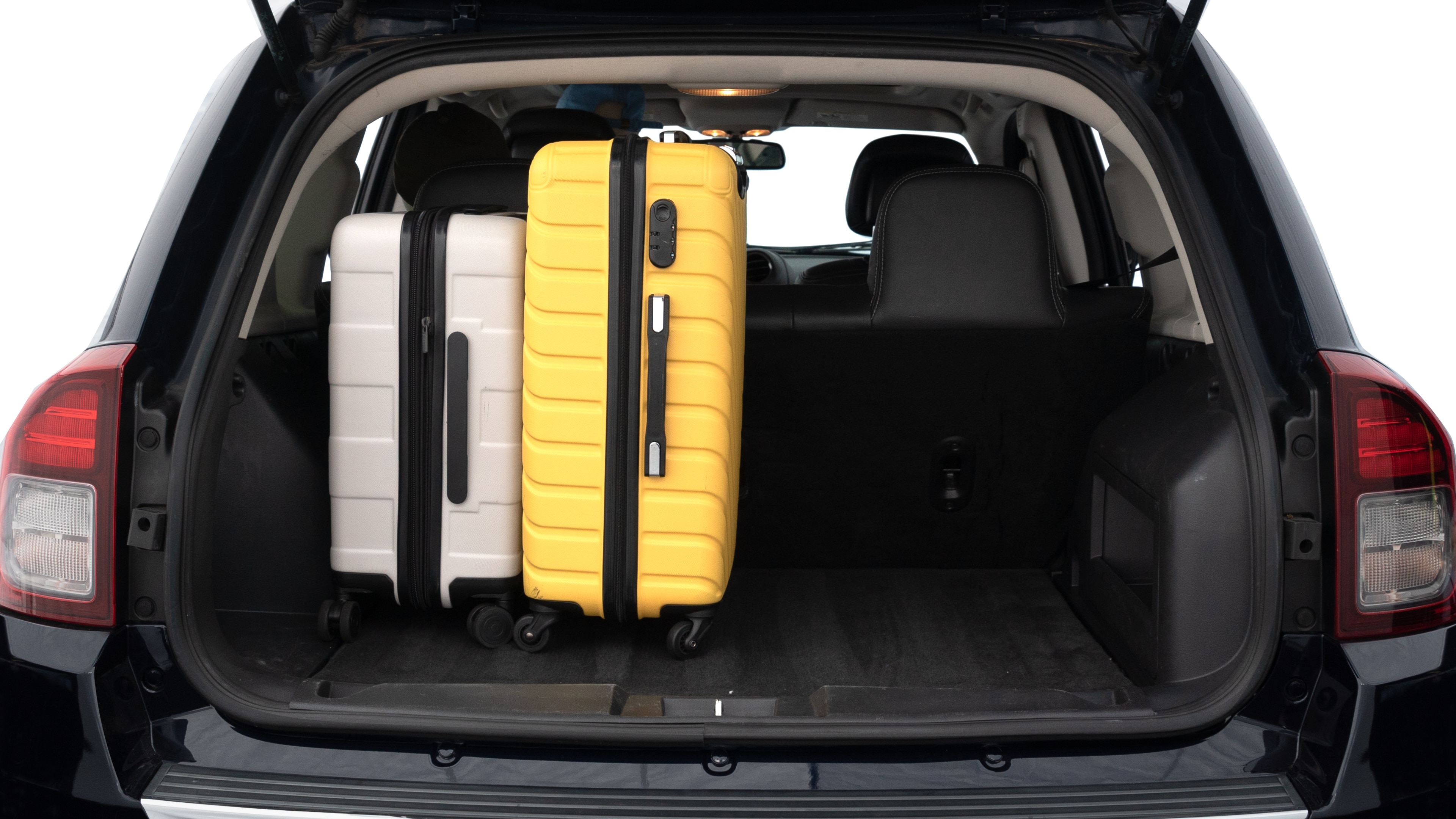 The trunk lid is open, showing full view of the trunk space. Two medium and two small suitcases are placed inside.