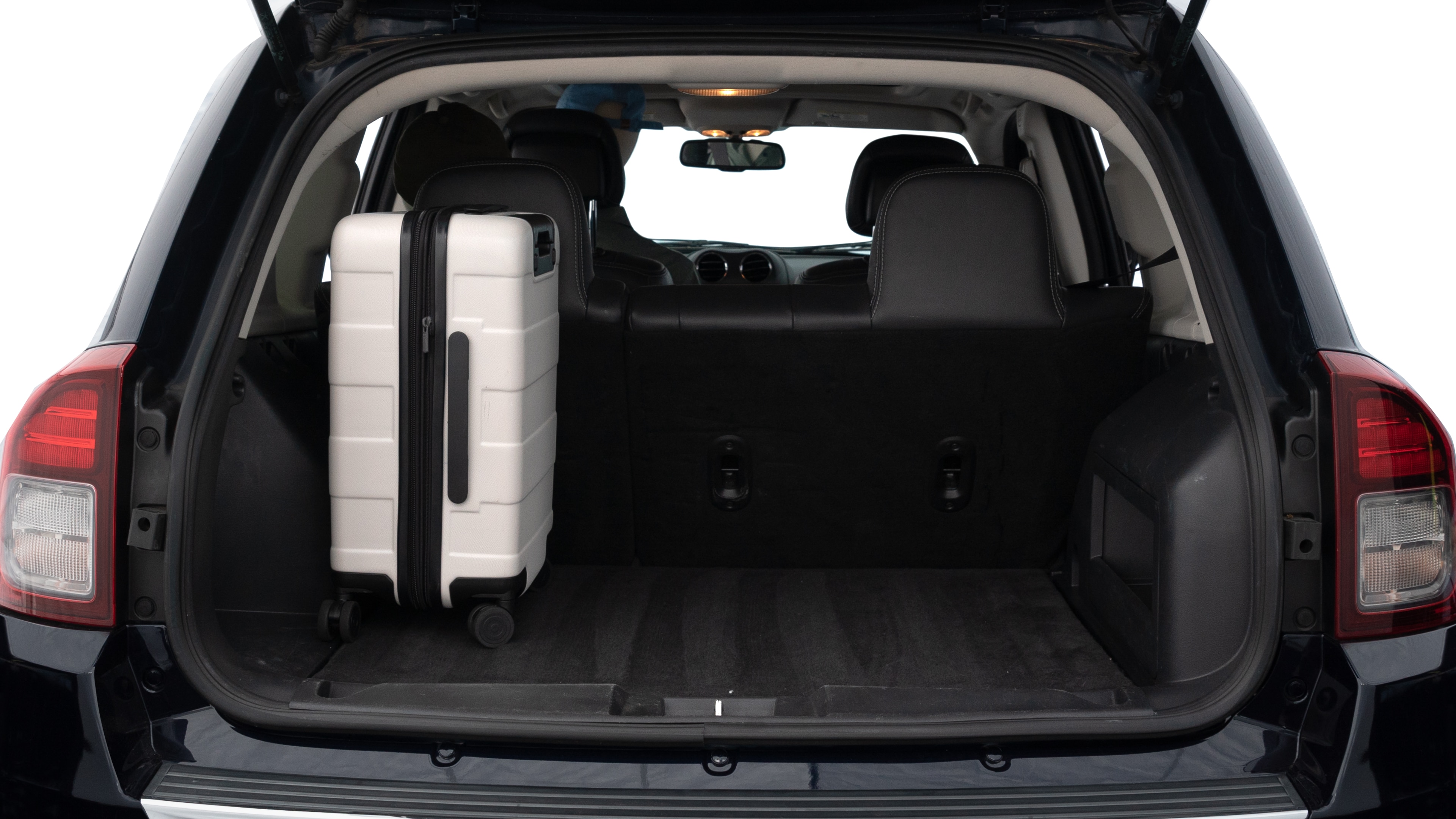 The trunk lid is open, showing full view of the trunk space. Two medium and two small suitcases are placed inside.
