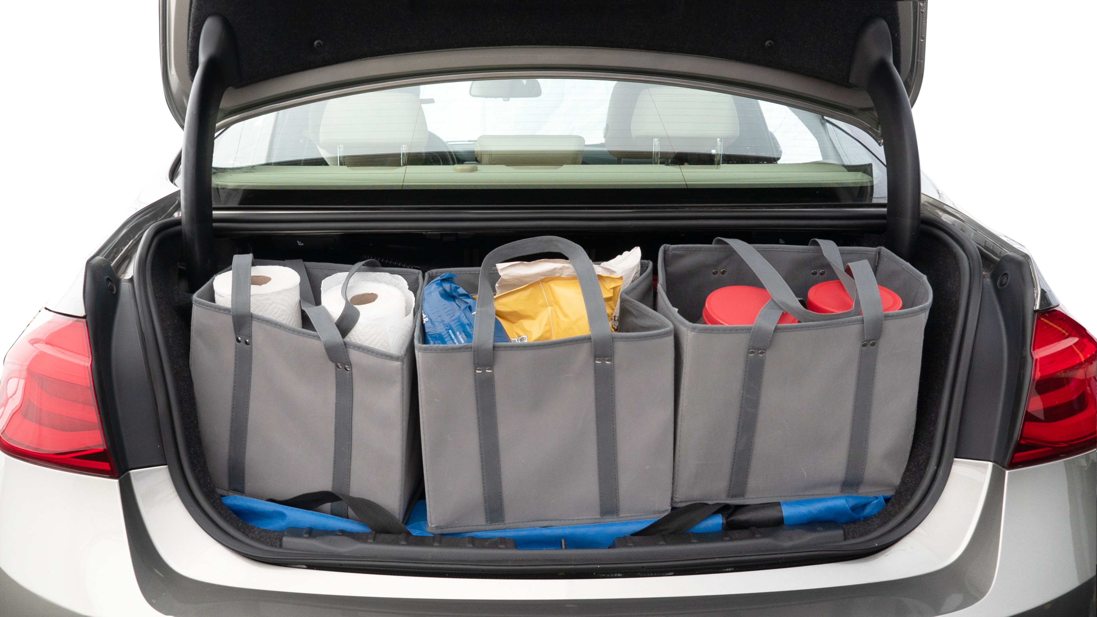 The trunk lid is open showing full view of the trunk. A baby stroller, three grocery carriers, two camping chairs in the carrying bag, and a set of golf clubs are placed inside.
