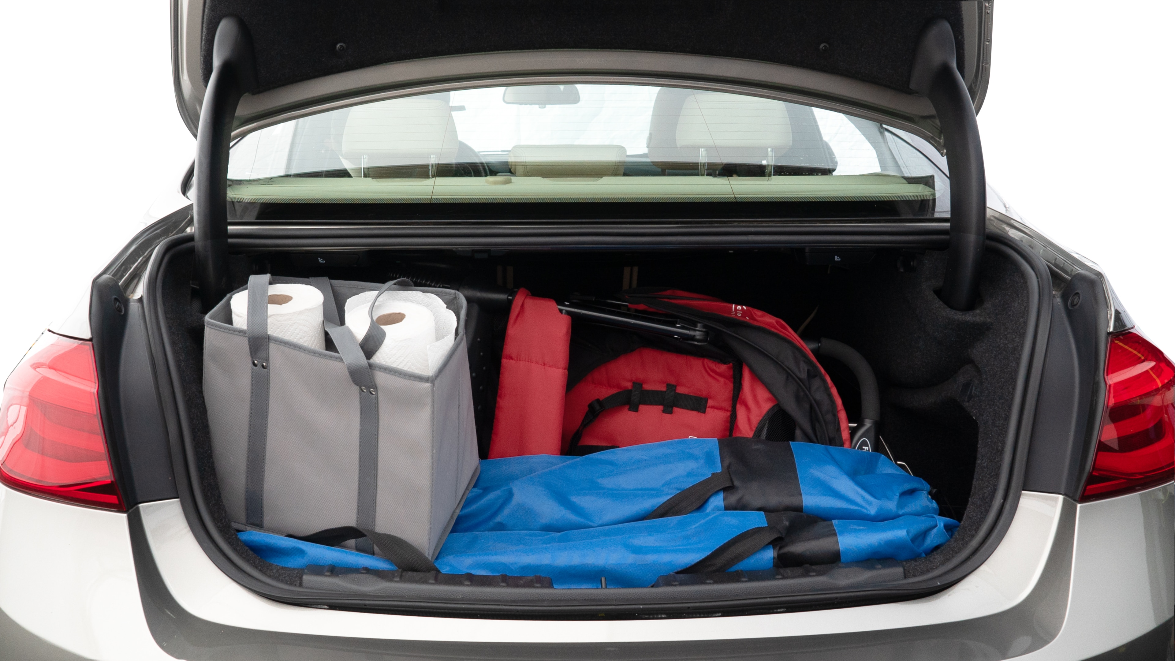 The trunk lid is open showing full view of the trunk. A baby stroller, three grocery carriers, two camping chairs in the carrying bag, and a set of golf clubs are placed inside.