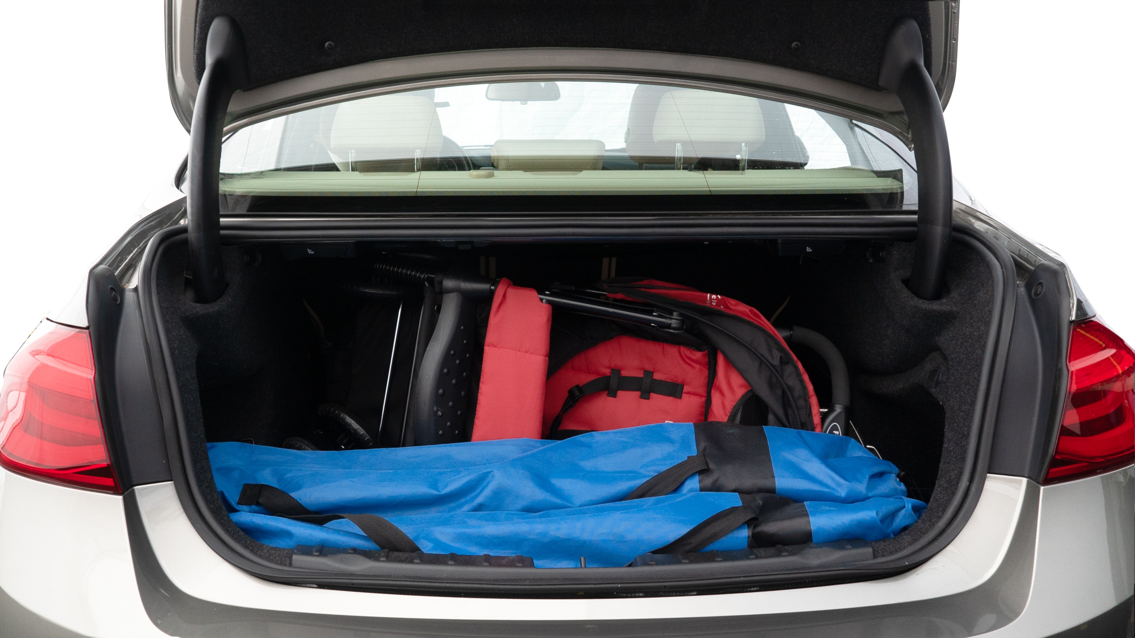 The trunk lid is open showing full view of the trunk. A baby stroller, three grocery carriers, two camping chairs in the carrying bag, and a set of golf clubs are placed inside.