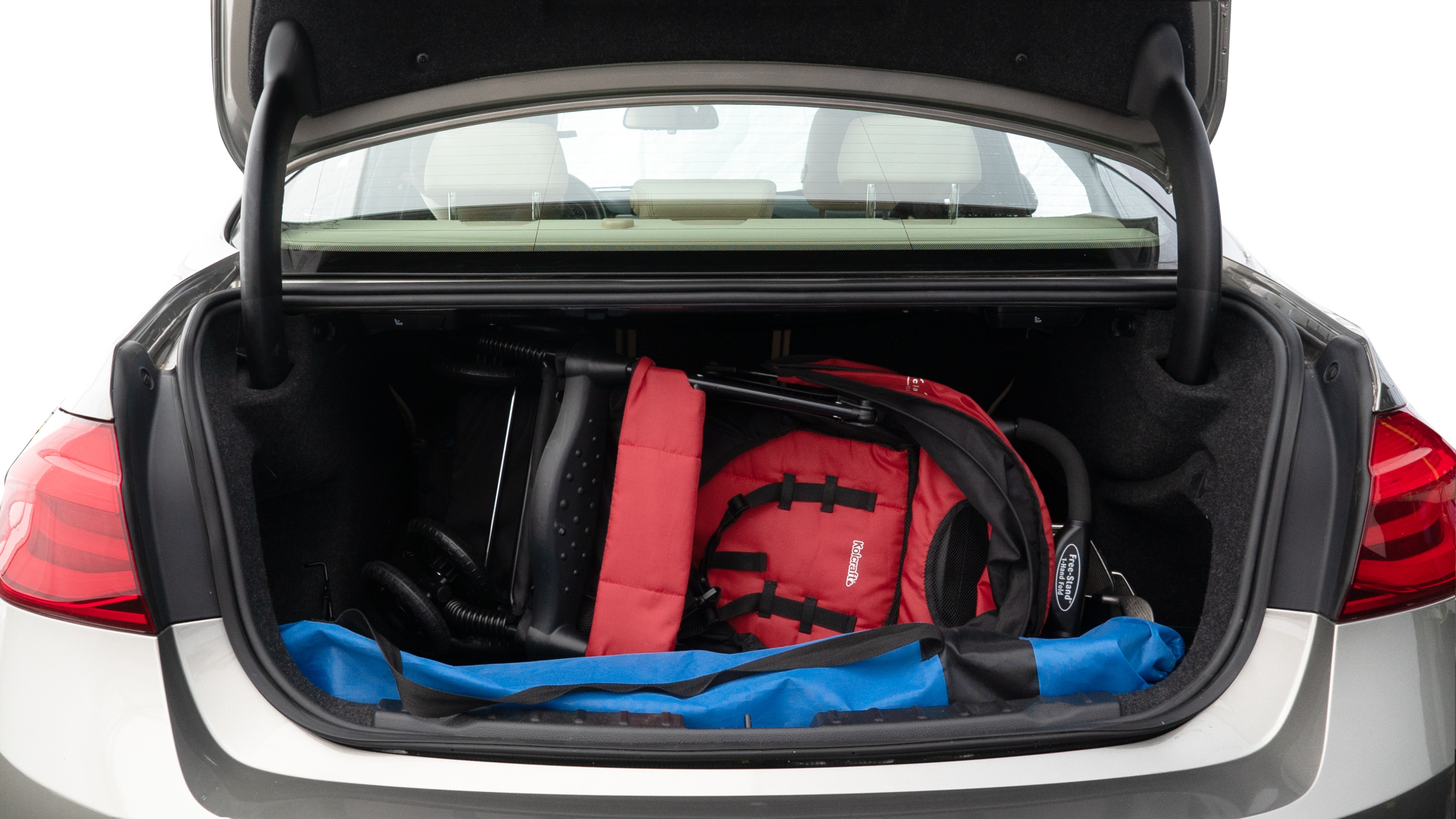 The trunk lid is open showing full view of the trunk. A baby stroller, three grocery carriers, two camping chairs in the carrying bag, and a set of golf clubs are placed inside.