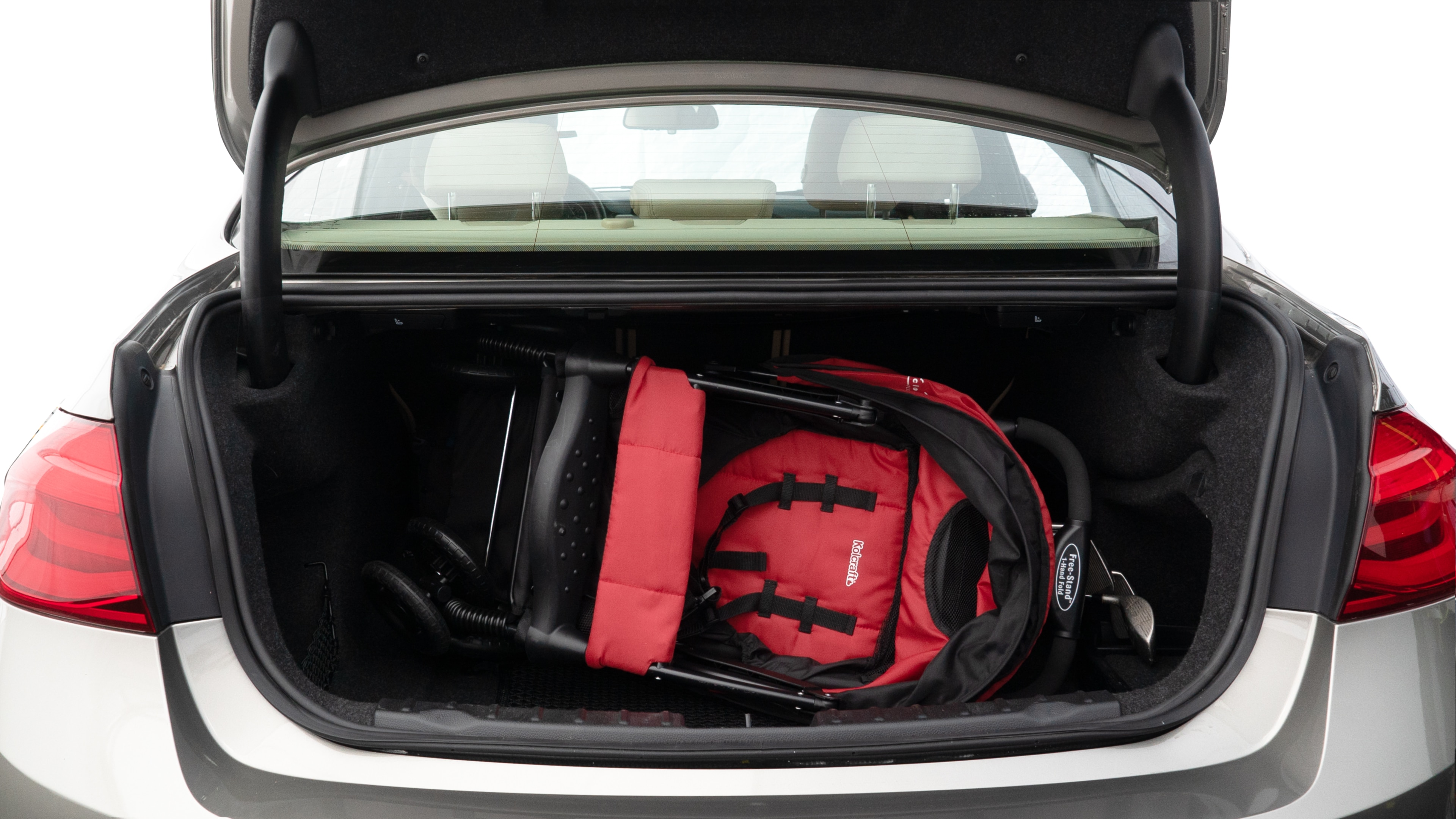 The trunk lid is open showing full view of the trunk. A baby stroller, three grocery carriers, two camping chairs in the carrying bag, and a set of golf clubs are placed inside.