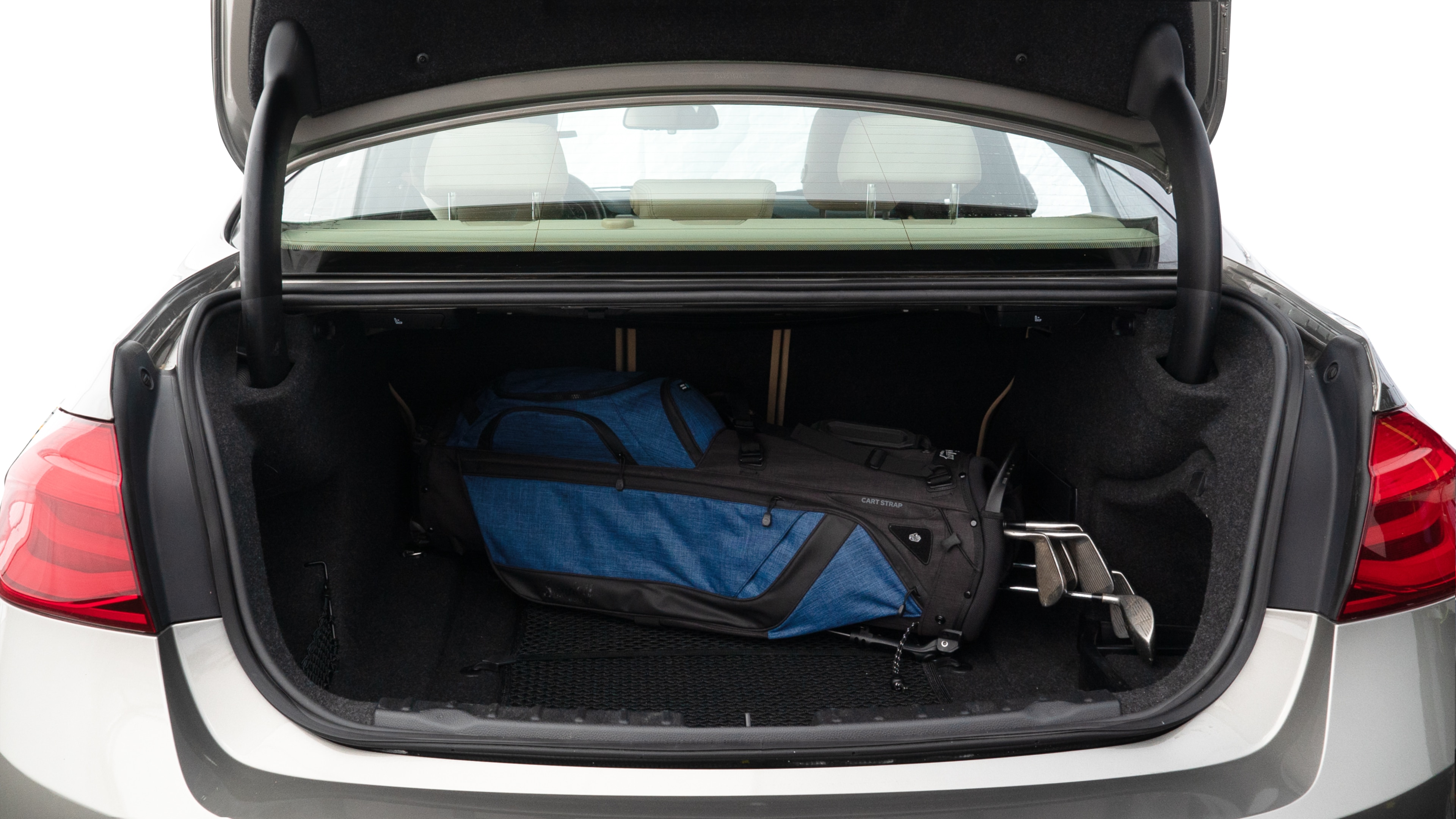 The trunk lid is open showing full view of the trunk. A baby stroller, three grocery carriers, two camping chairs in the carrying bag, and a set of golf clubs are placed inside.