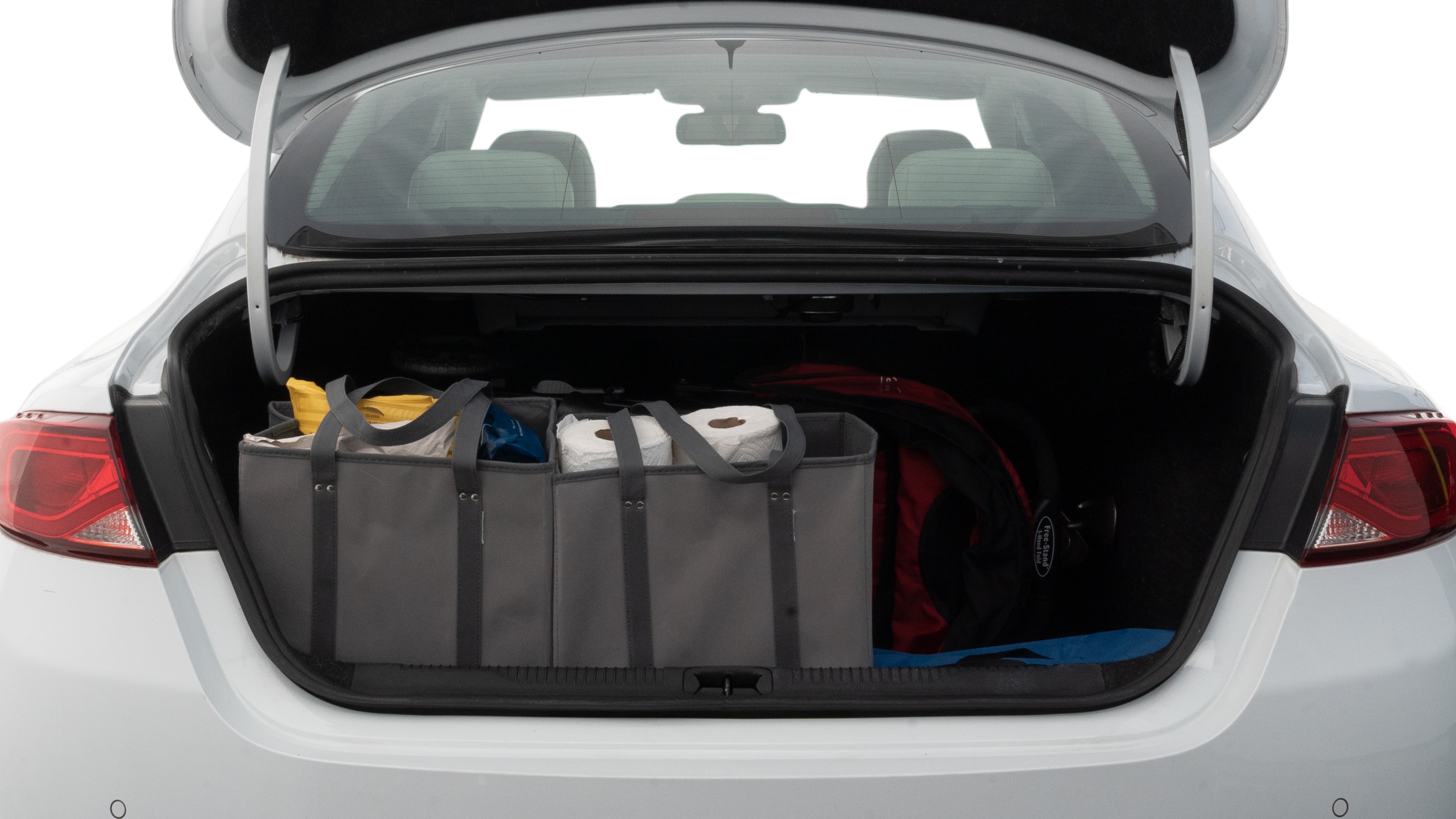 The trunk lid is open showing full view of the trunk. A baby stroller, three grocery carriers, two camping chairs in the carrying bag, and a set of golf clubs are placed inside.