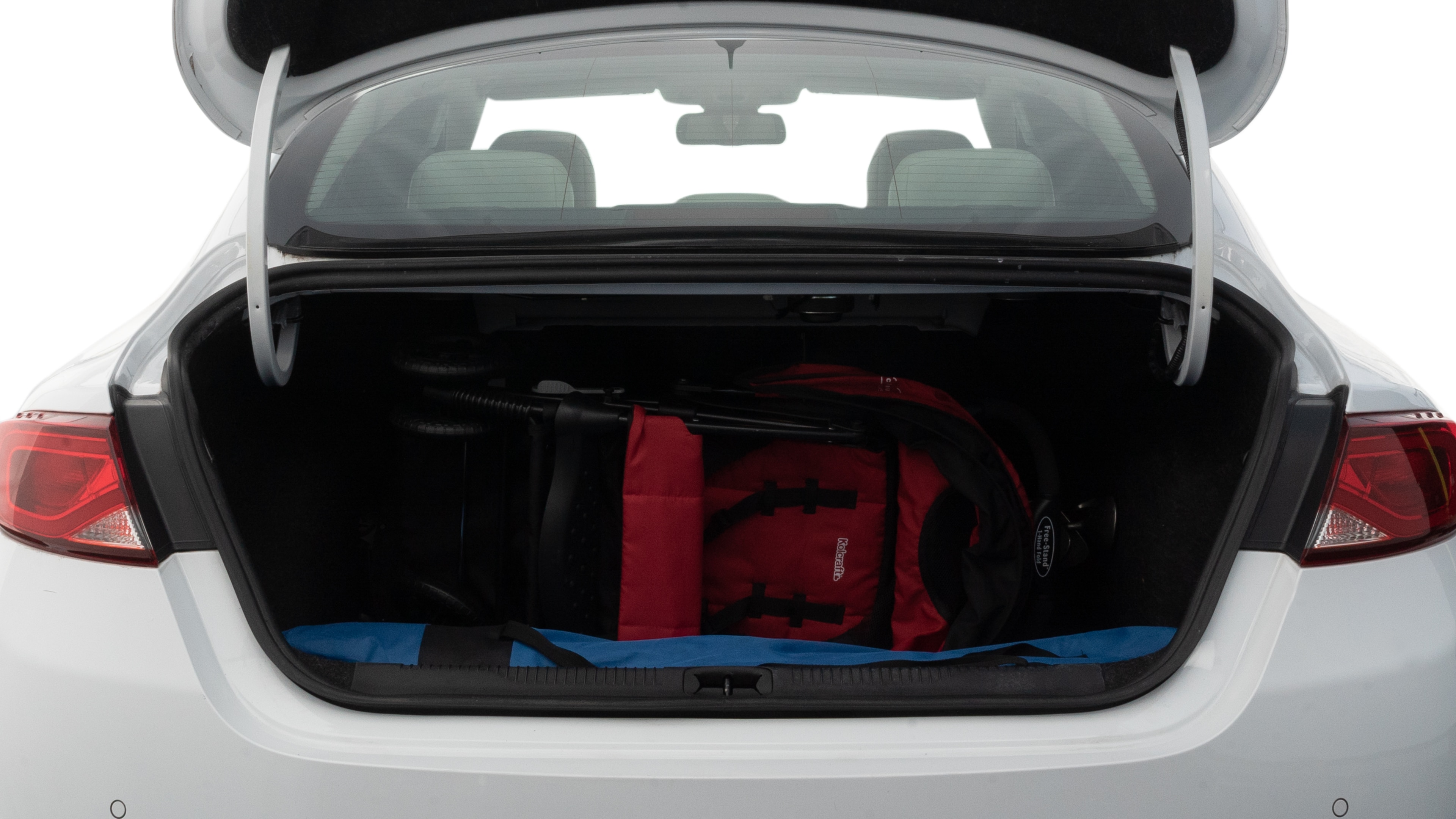The trunk lid is open showing full view of the trunk. A baby stroller, three grocery carriers, two camping chairs in the carrying bag, and a set of golf clubs are placed inside.