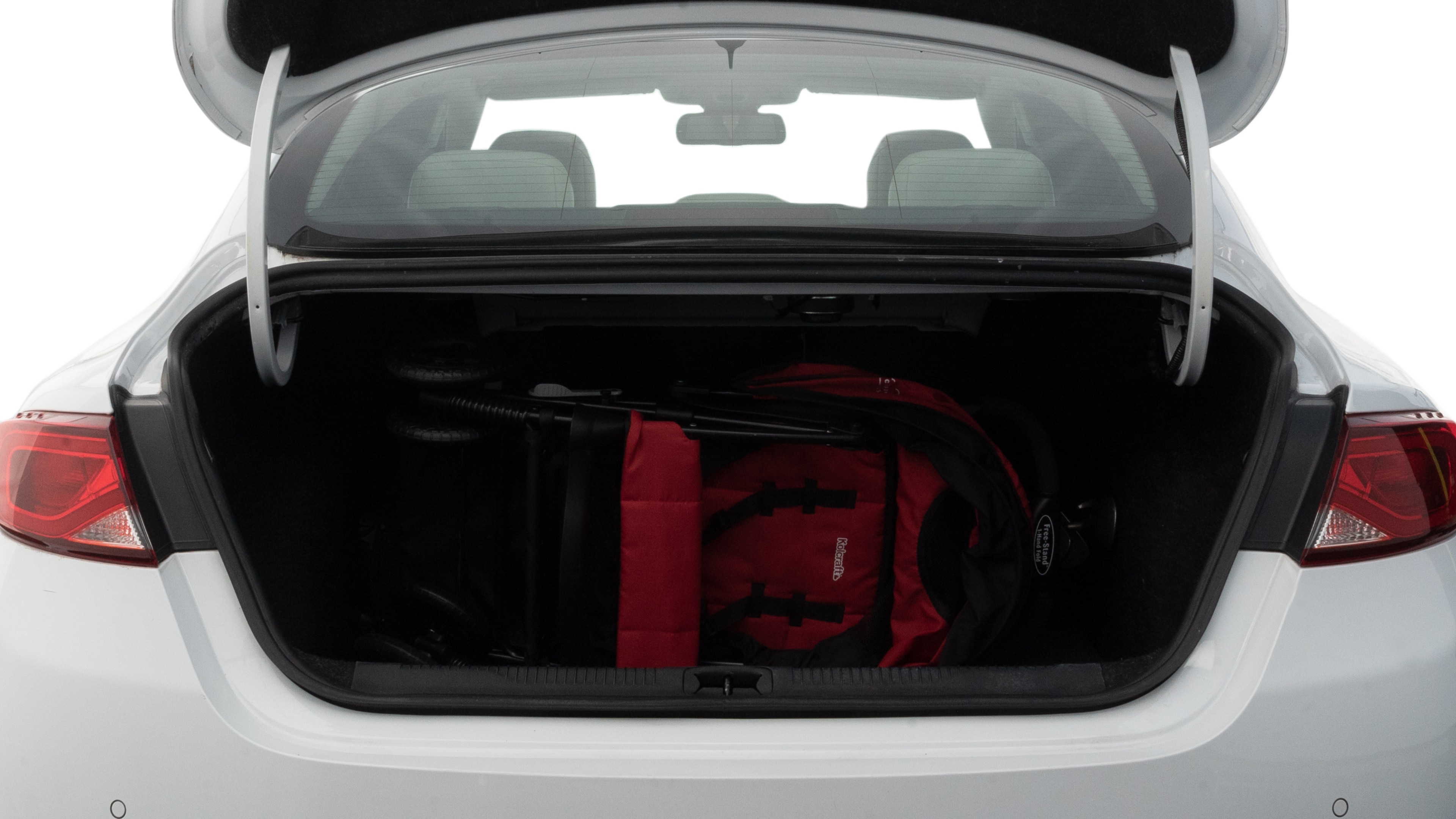 The trunk lid is open showing full view of the trunk. A baby stroller, three grocery carriers, two camping chairs in the carrying bag, and a set of golf clubs are placed inside.