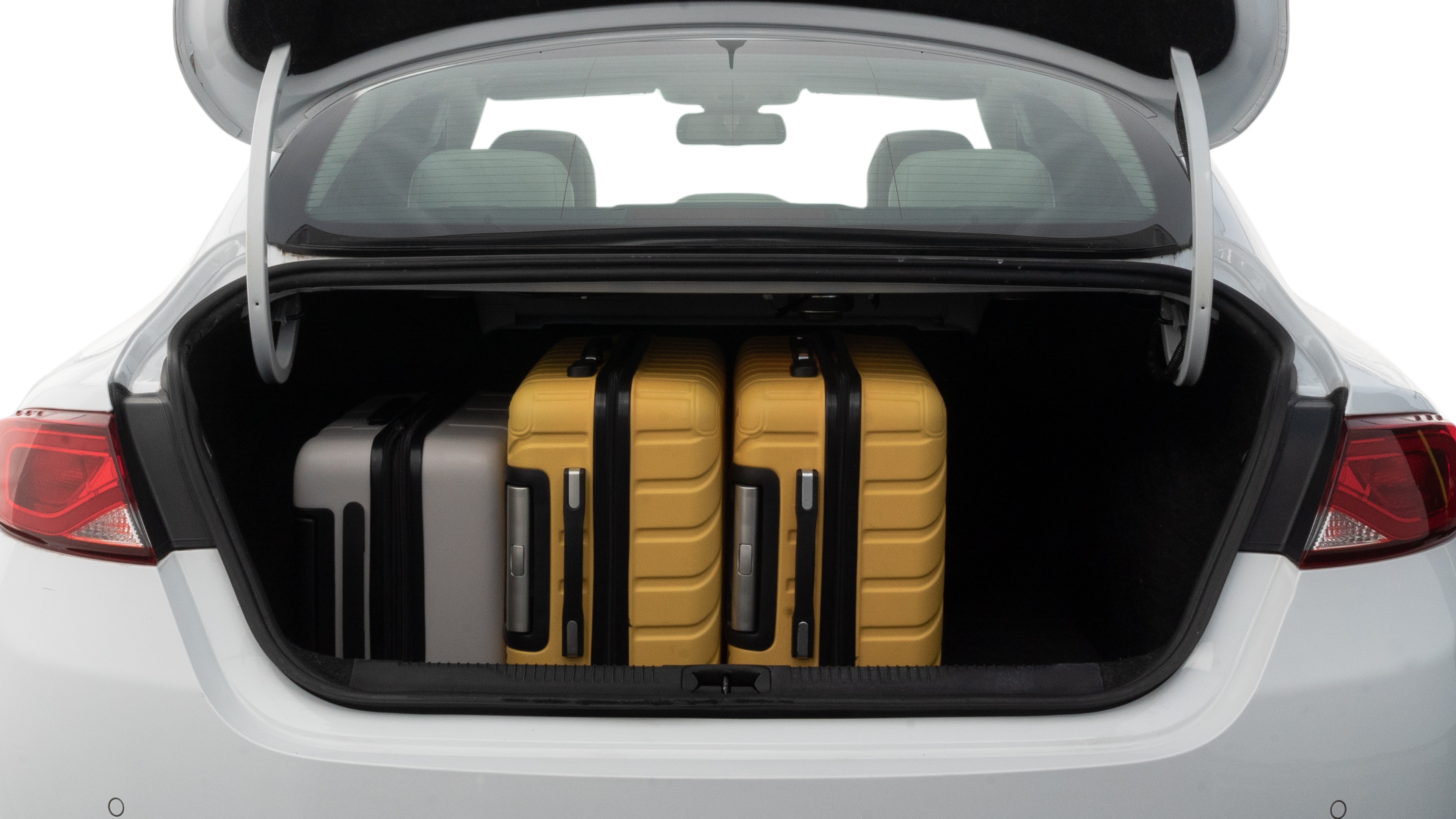 The trunk lid is open, showing full view of the trunk space. Two medium and two small suitcases are placed inside.