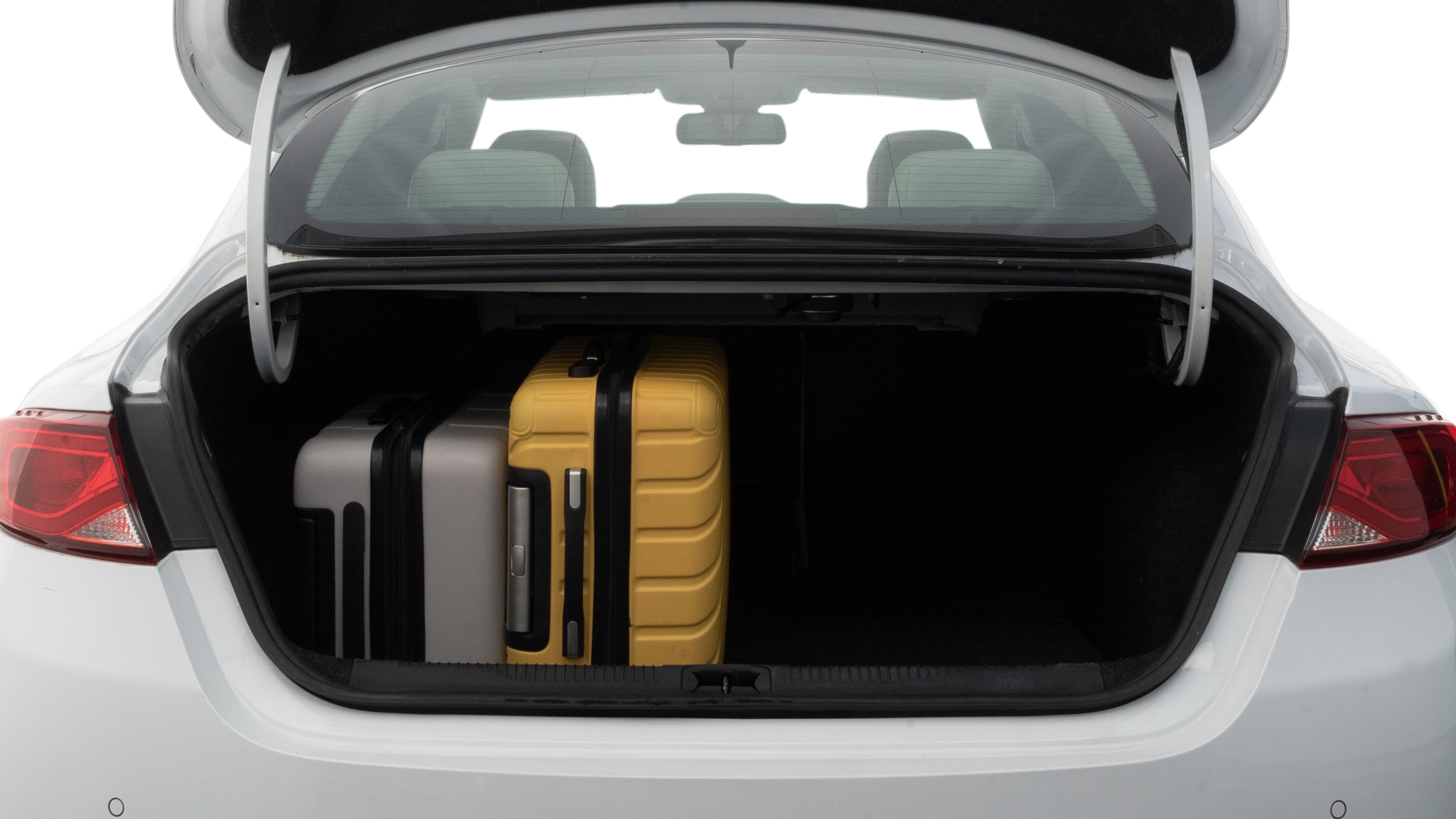 The trunk lid is open, showing full view of the trunk space. Two medium and two small suitcases are placed inside.