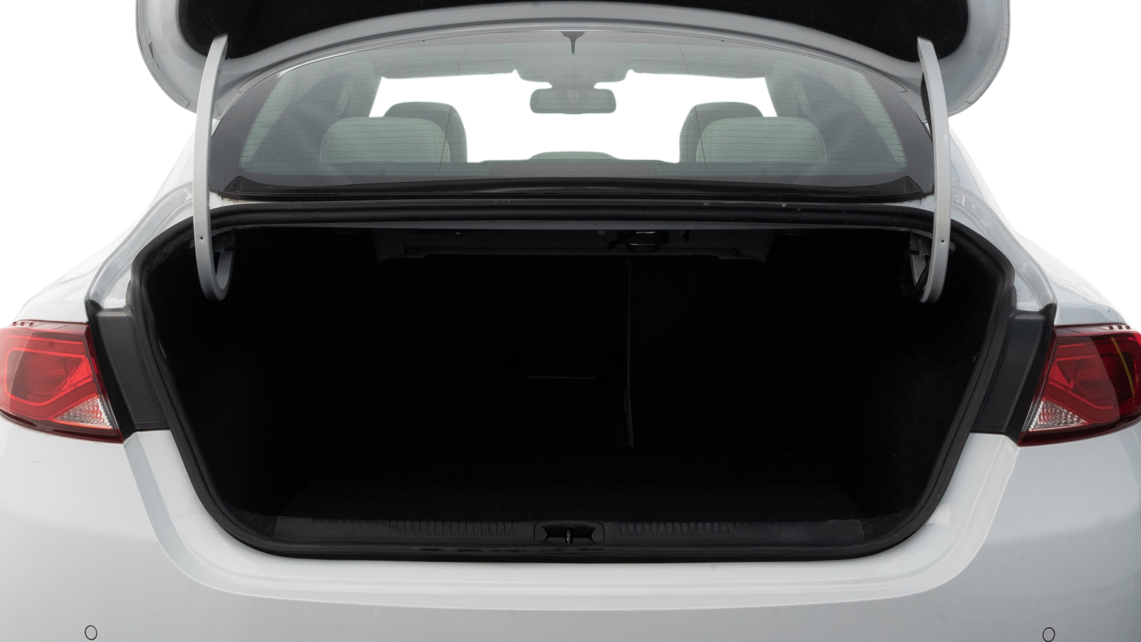 The trunk lid is open, showing full view of the trunk space. Two medium and two small suitcases are placed inside.