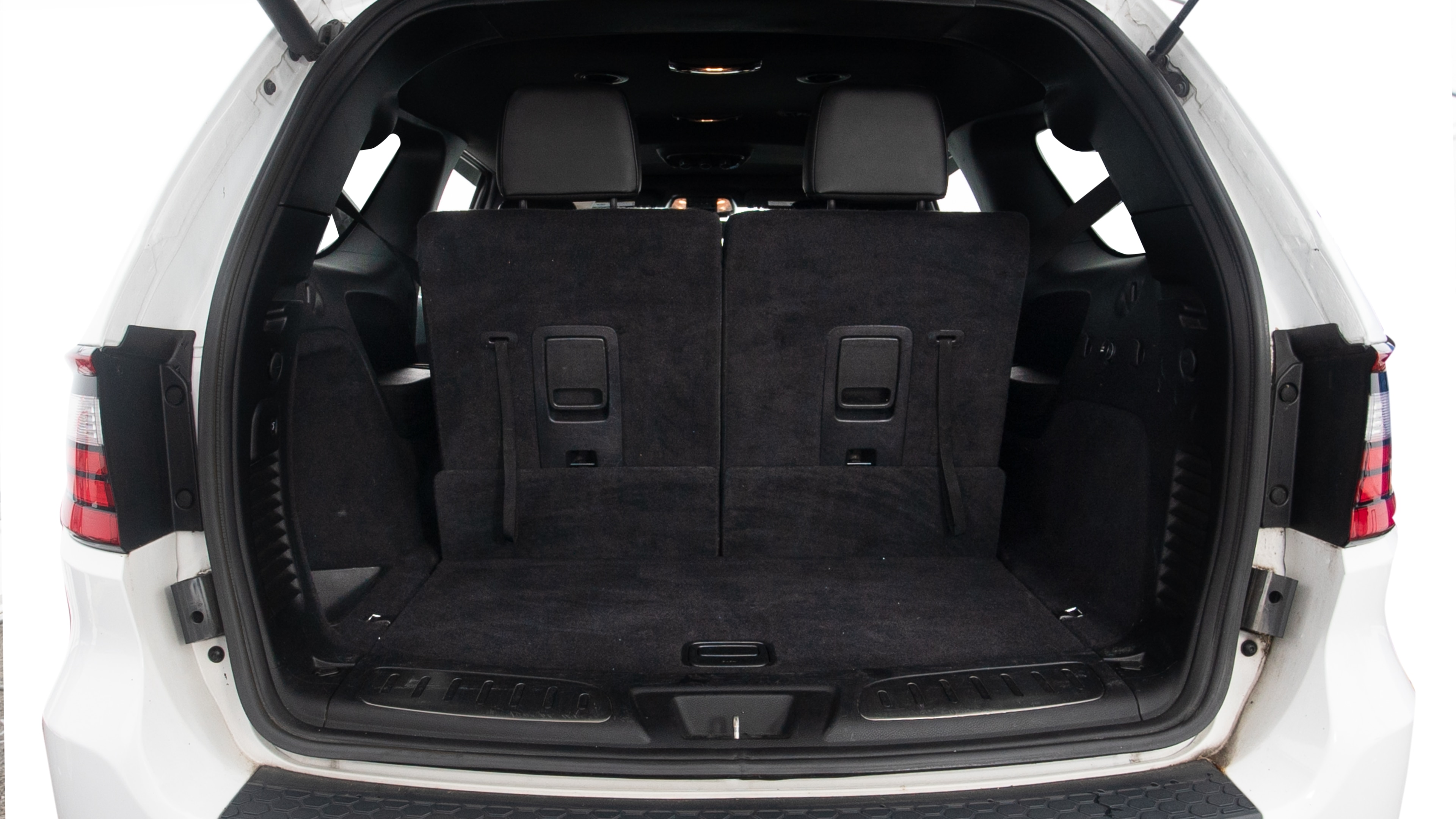 The trunk lid is open showing full view of the trunk. Three grocery carriers, two camping chairs in the carrying bag, and a set of golf clubs are placed inside.