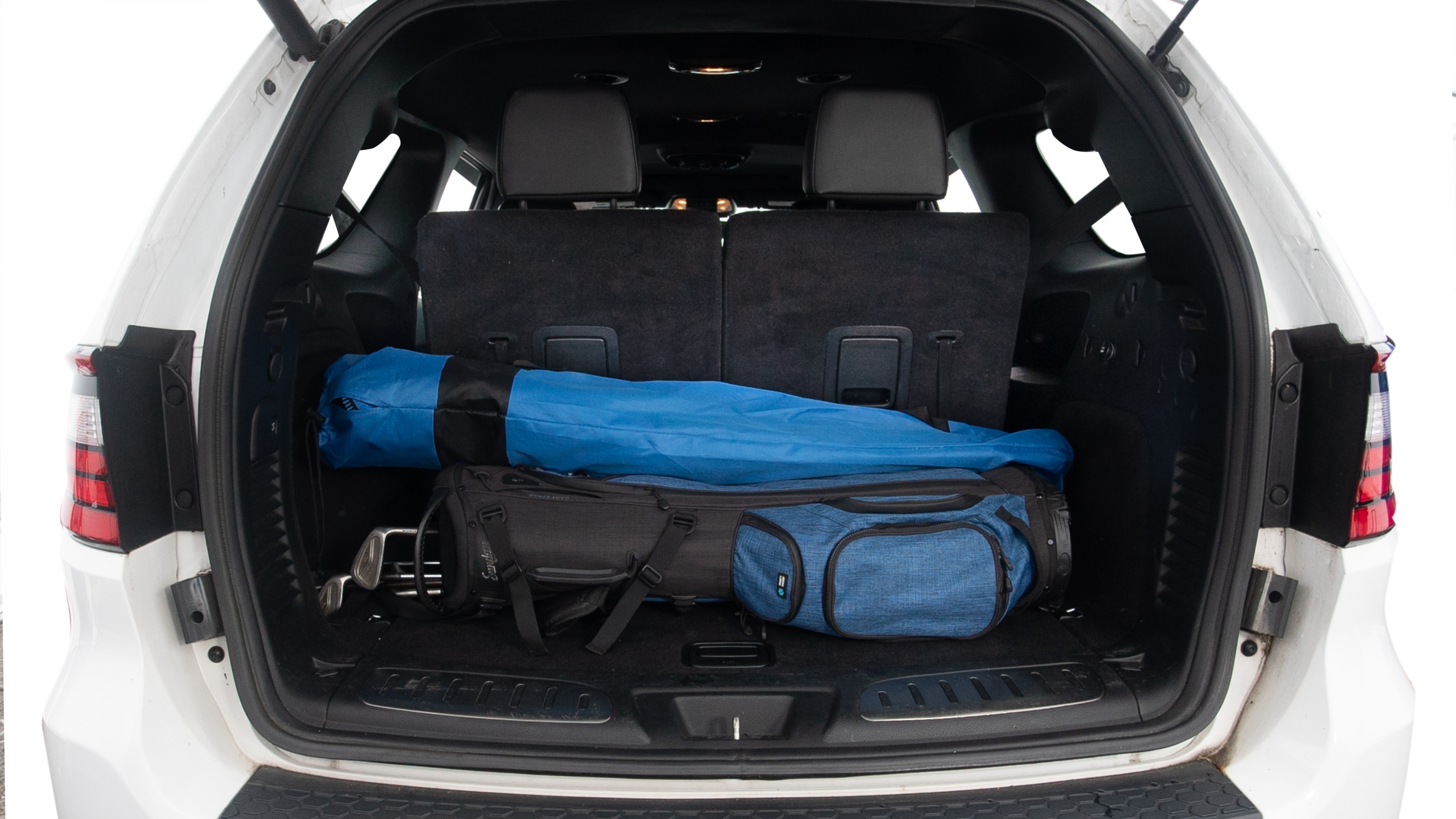 The trunk lid is open showing full view of the trunk. Three grocery carriers, two camping chairs in the carrying bag, and a set of golf clubs are placed inside.
