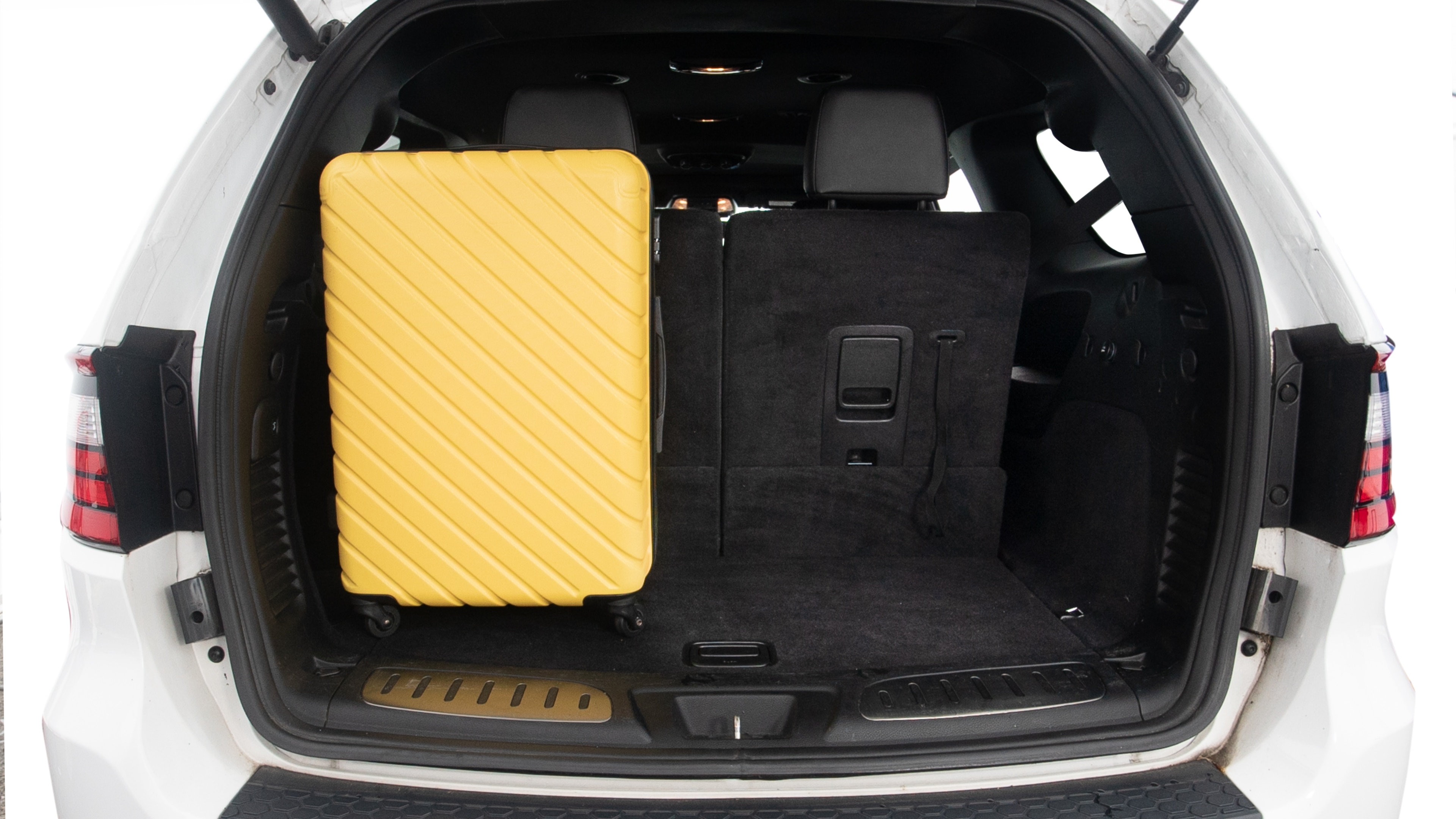 The trunk lid is open, showing full view of the trunk space. One large and two small suitcases are placed inside.