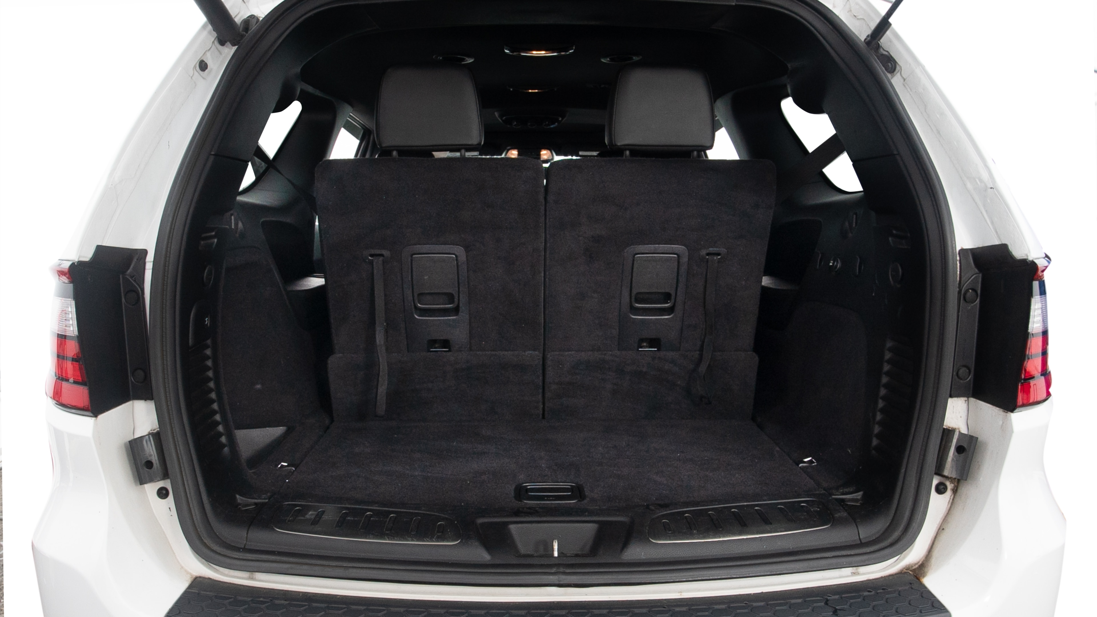 The trunk lid is open, showing full view of the trunk space. One large and two small suitcases are placed inside.