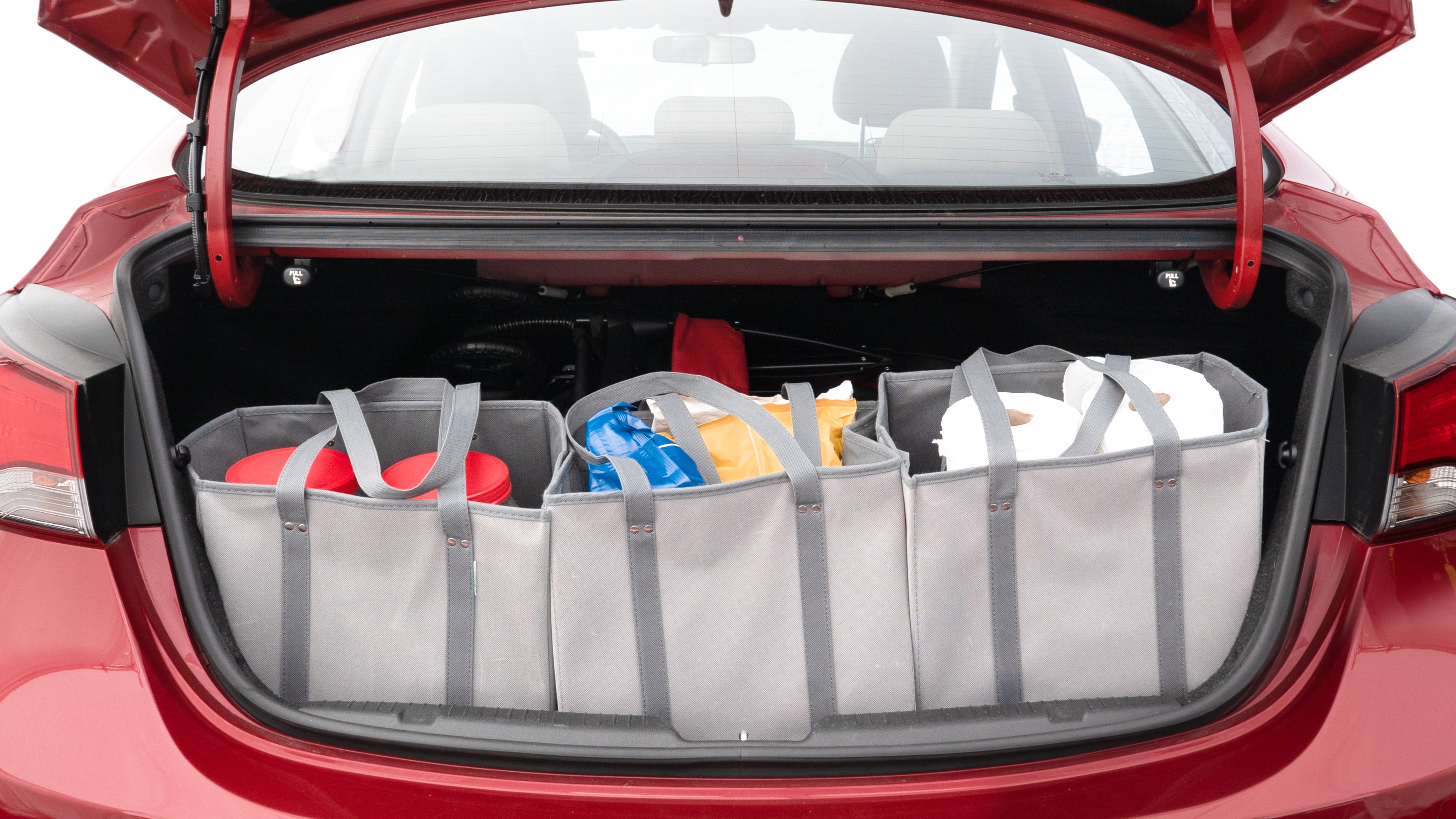 The trunk lid is open showing full view of the trunk. A baby stroller, three grocery carriers, two camping chairs in the carrying bag, and a set of golf clubs are placed inside.