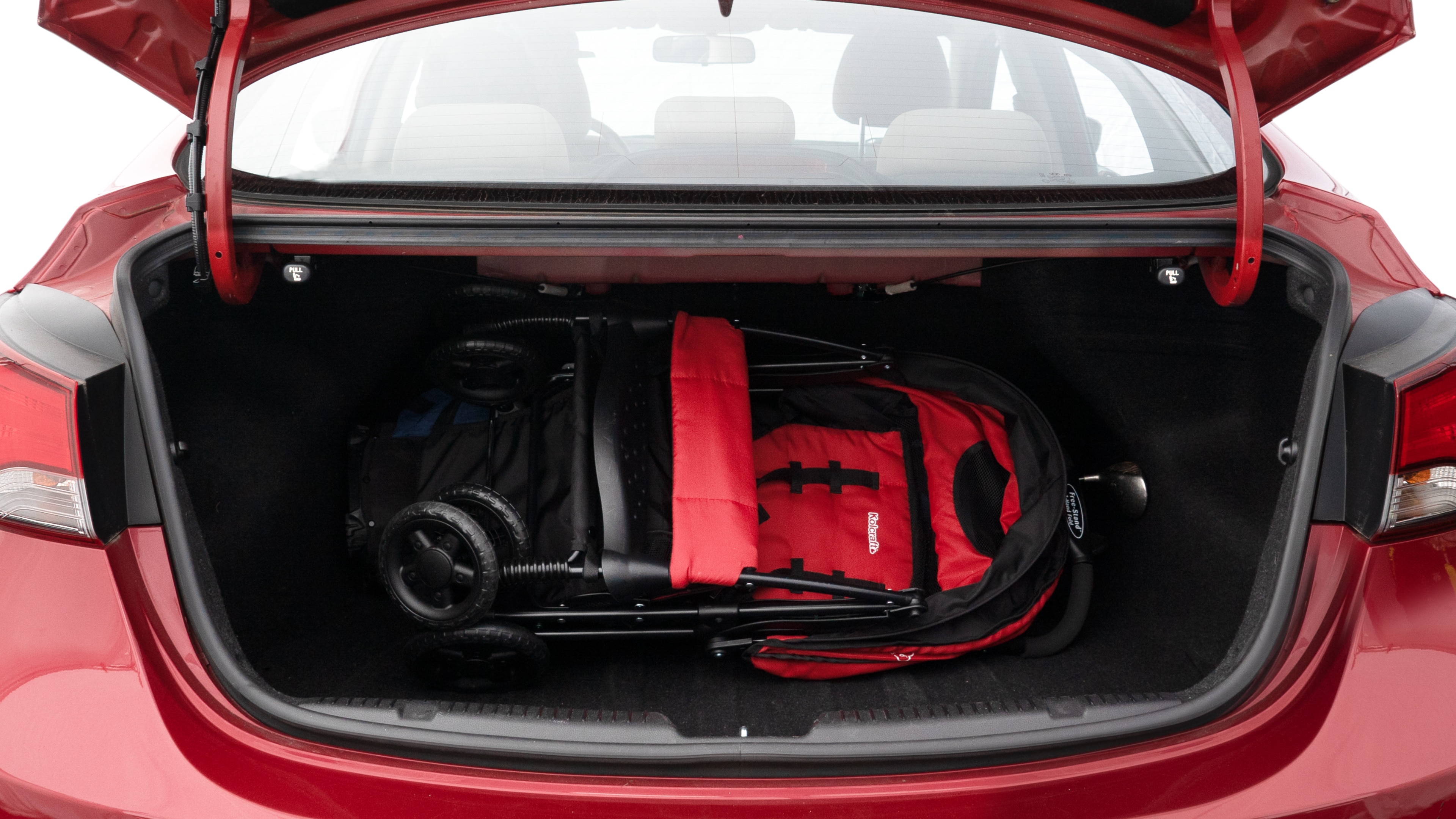 The trunk lid is open showing full view of the trunk. A baby stroller, three grocery carriers, two camping chairs in the carrying bag, and a set of golf clubs are placed inside.