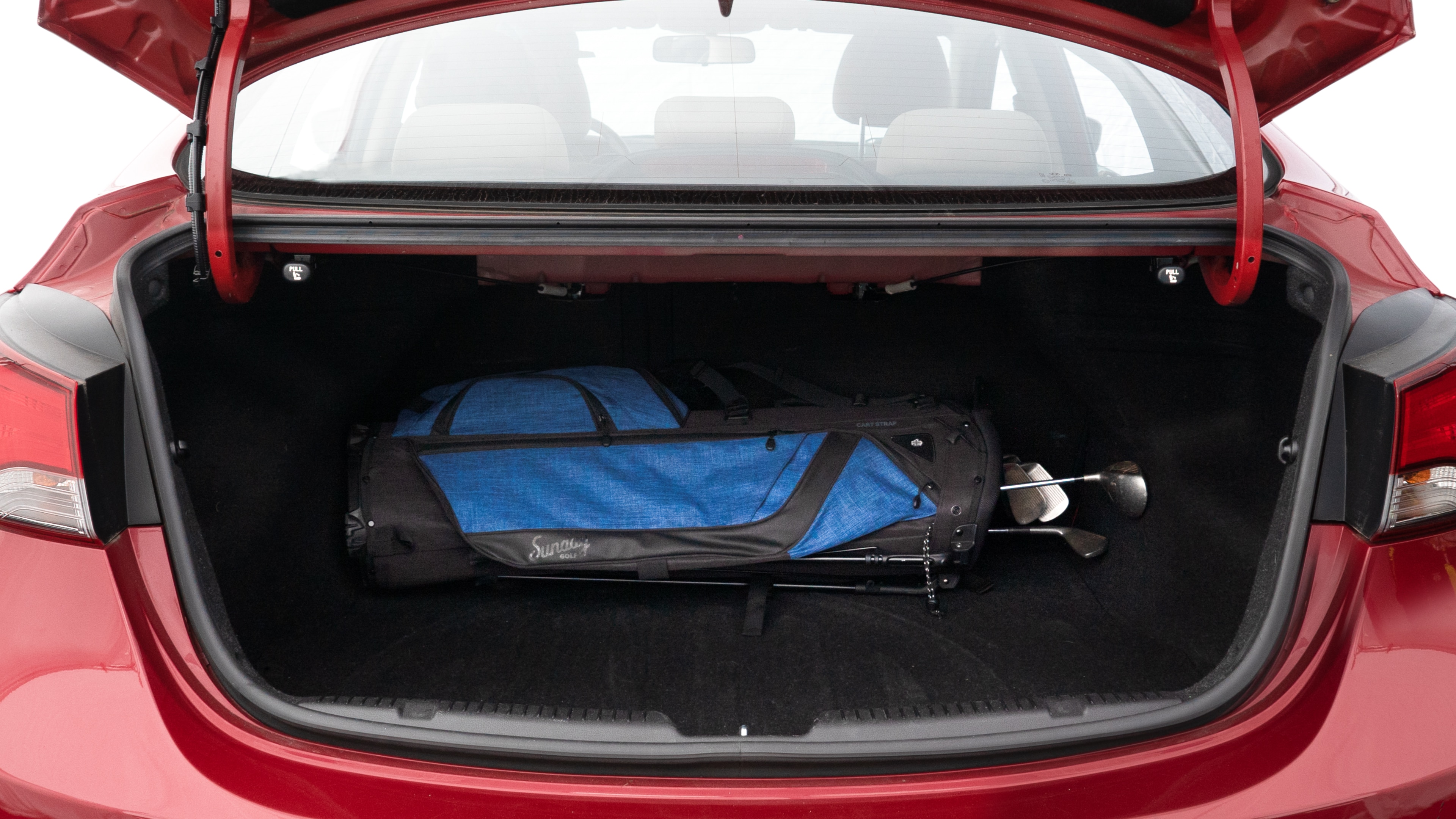 The trunk lid is open showing full view of the trunk. A baby stroller, three grocery carriers, two camping chairs in the carrying bag, and a set of golf clubs are placed inside.