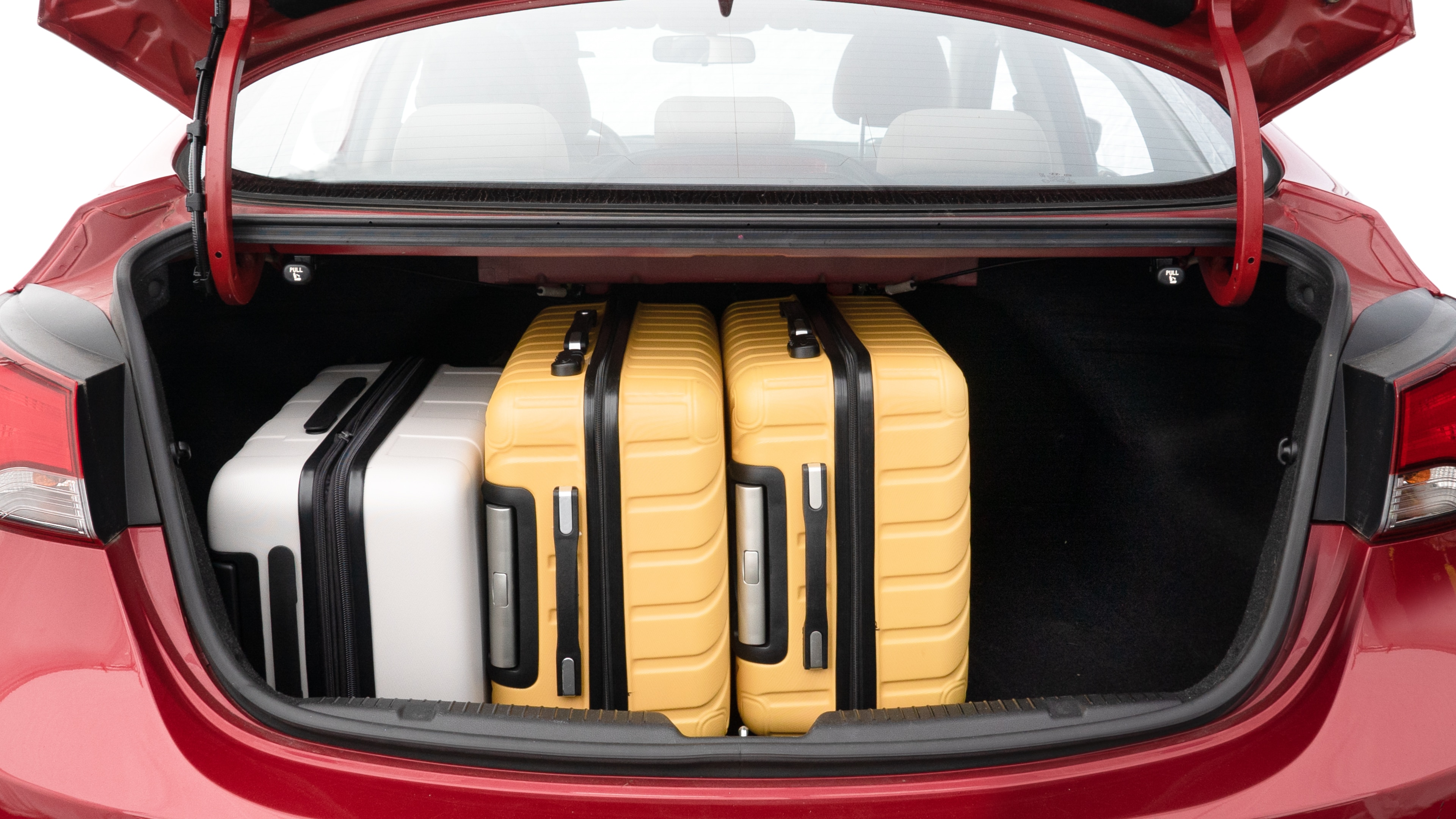 The trunk lid is open, showing full view of the trunk space. Two medium and two small suitcases are placed inside.