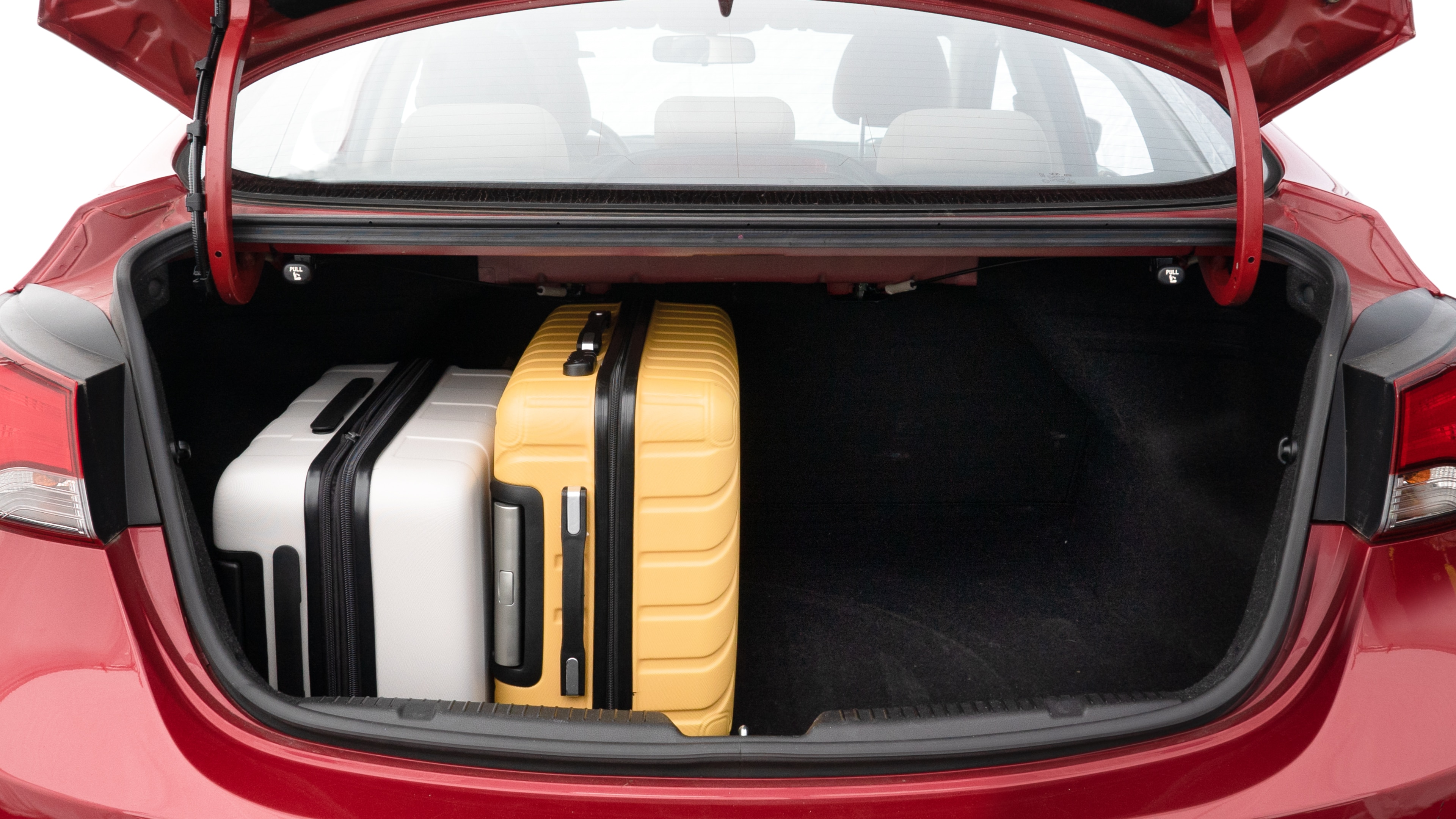 The trunk lid is open, showing full view of the trunk space. Two medium and two small suitcases are placed inside.