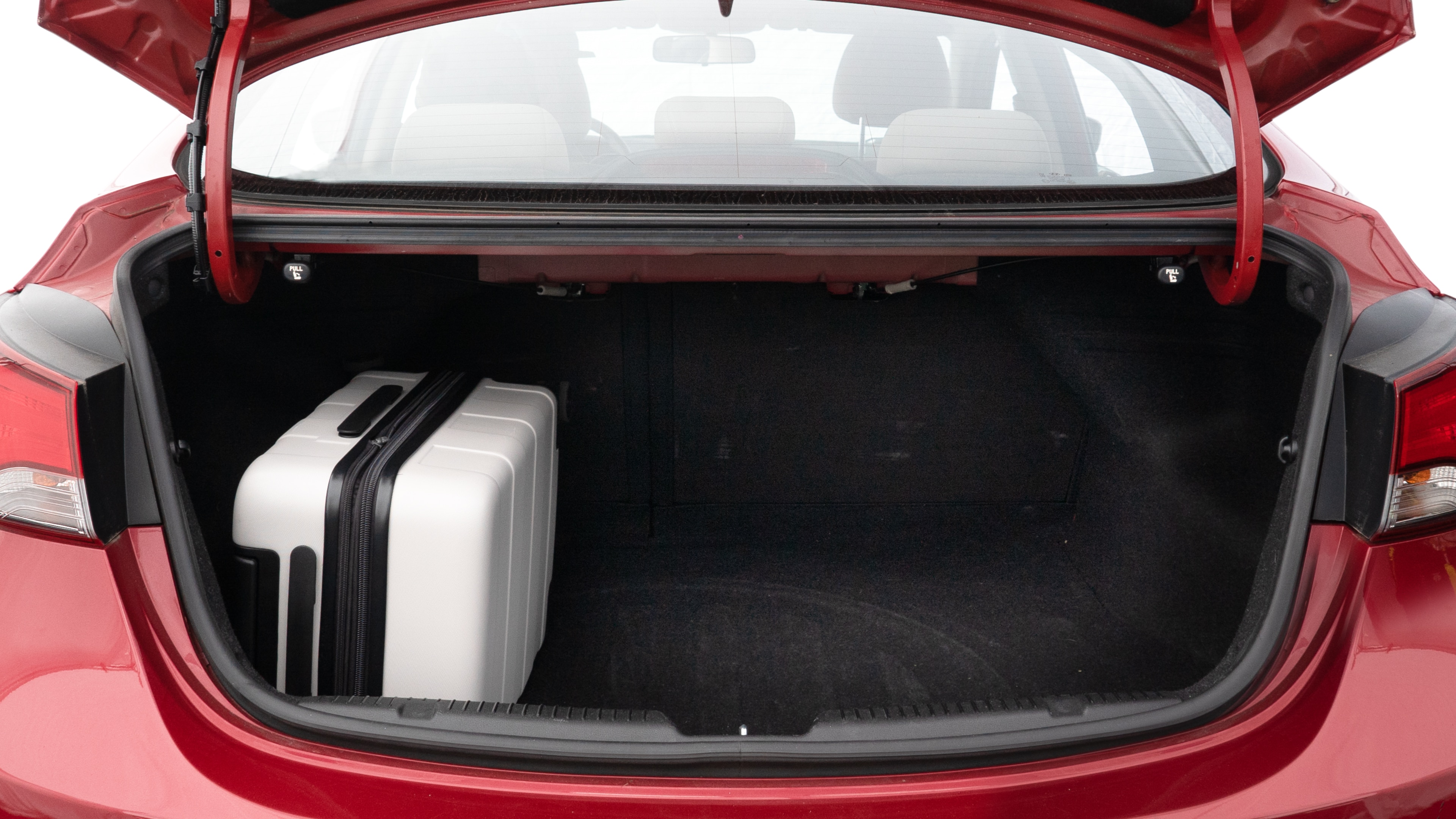 The trunk lid is open, showing full view of the trunk space. Two medium and two small suitcases are placed inside.