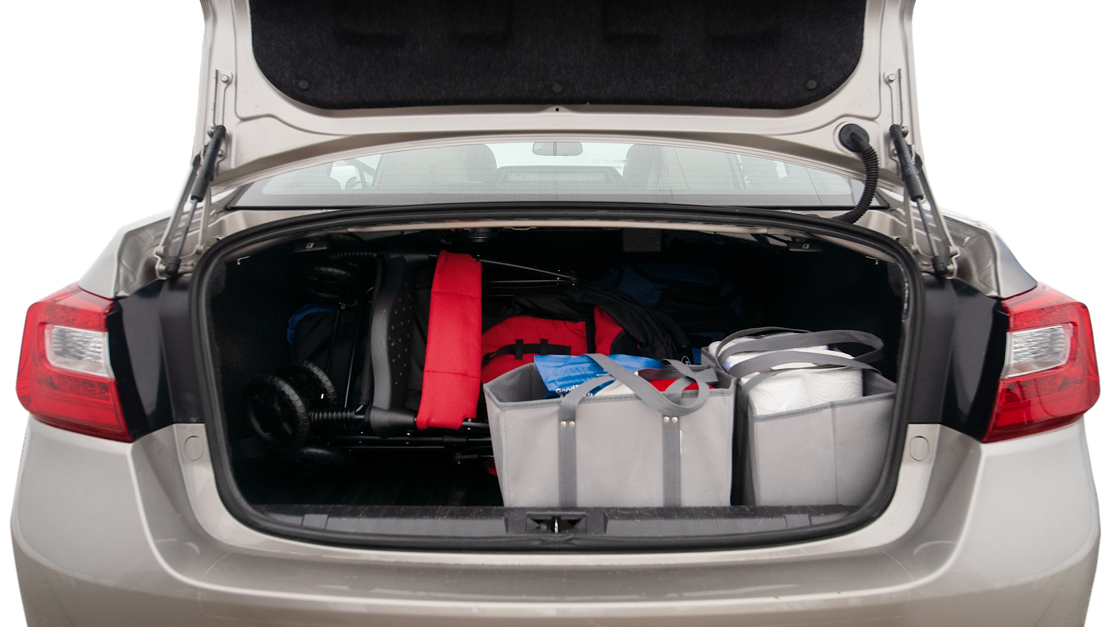 The trunk lid is open showing full view of the trunk. A baby stroller, three grocery carriers, two camping chairs in the carrying bag, and a set of golf clubs are placed inside.