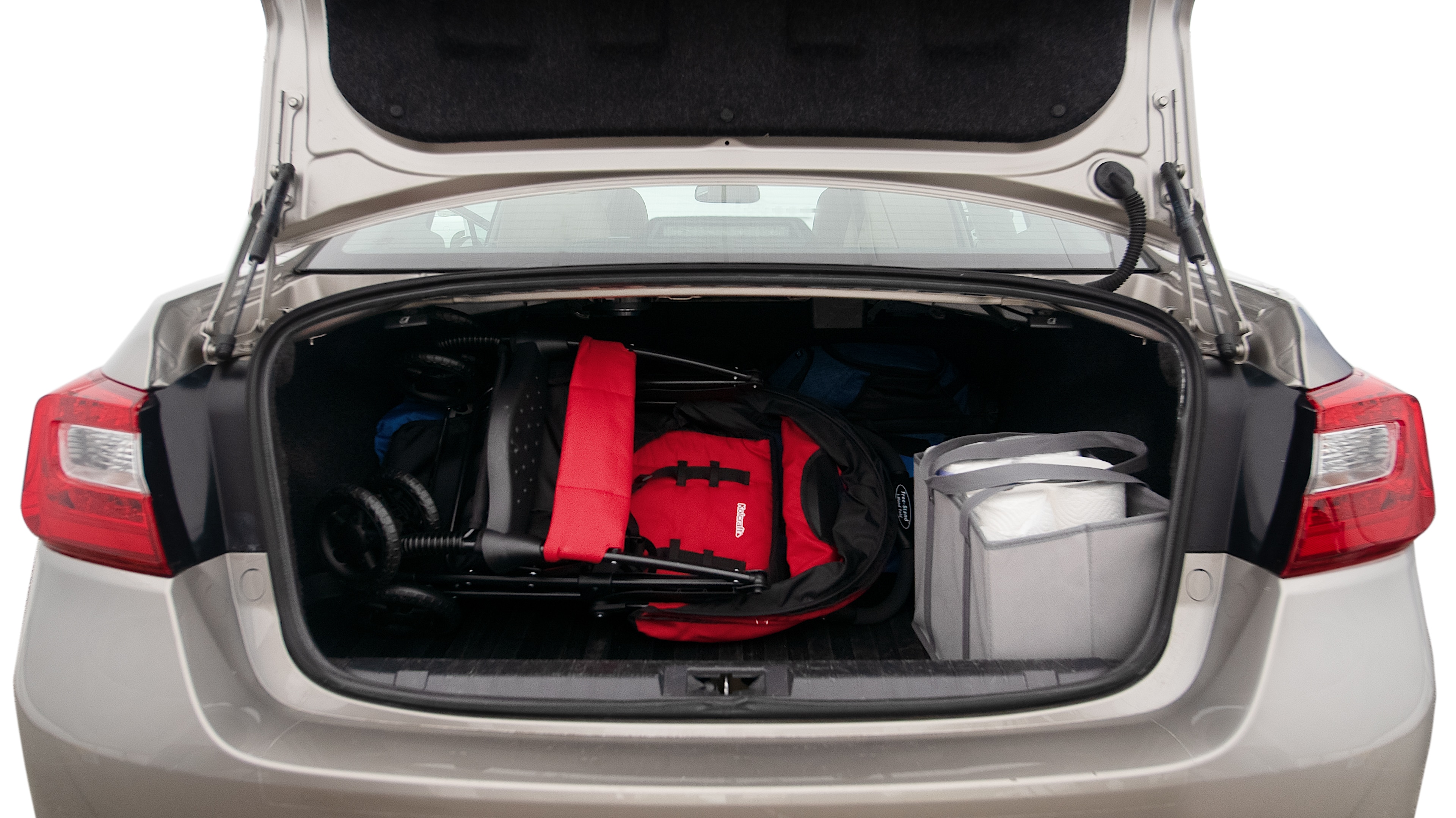 The trunk lid is open showing full view of the trunk. A baby stroller, three grocery carriers, two camping chairs in the carrying bag, and a set of golf clubs are placed inside.