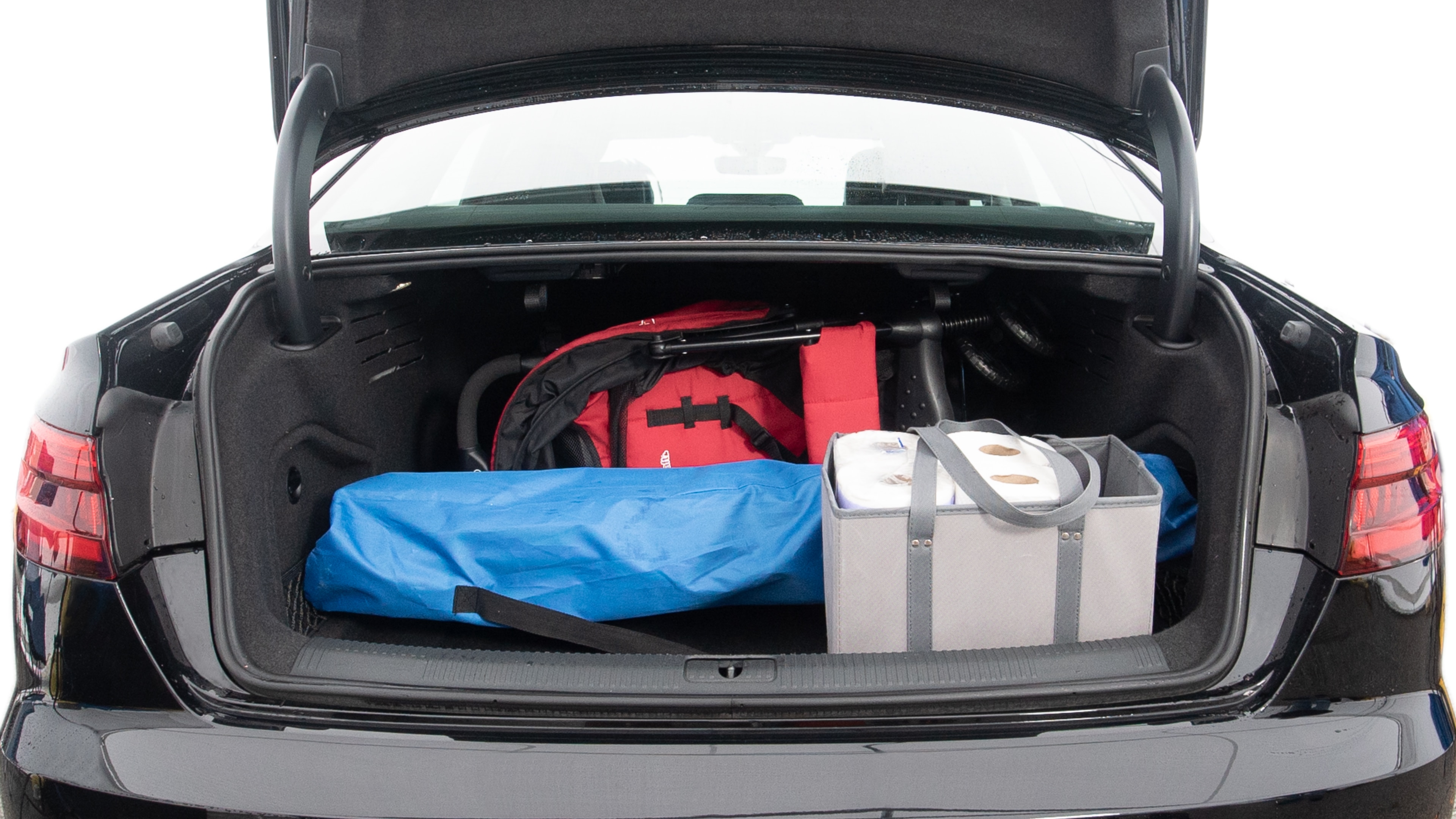 The trunk lid is open showing full view of the trunk. A baby stroller, two grocery carriers, one camping chairs in the carrying bag, and a set of golf clubs are placed inside.
