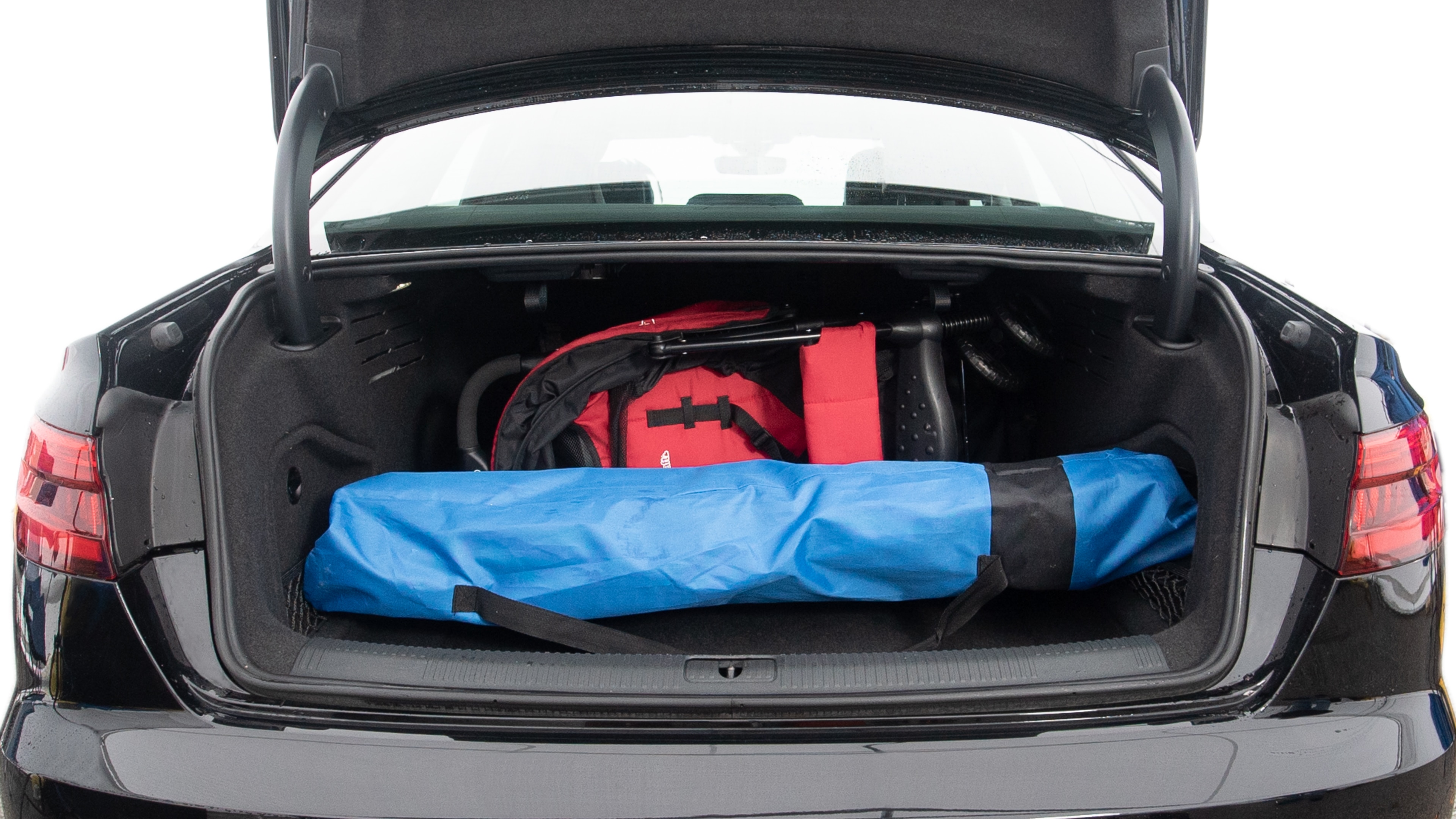 The trunk lid is open showing full view of the trunk. A baby stroller, two grocery carriers, one camping chairs in the carrying bag, and a set of golf clubs are placed inside.