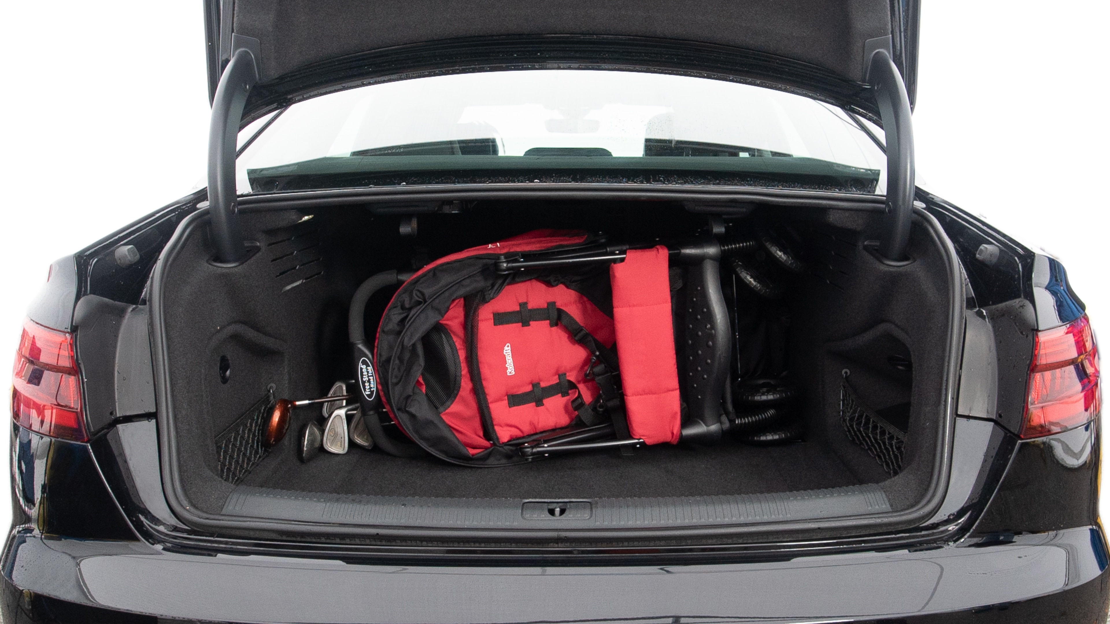 The trunk lid is open showing full view of the trunk. A baby stroller, two grocery carriers, one camping chairs in the carrying bag, and a set of golf clubs are placed inside.
