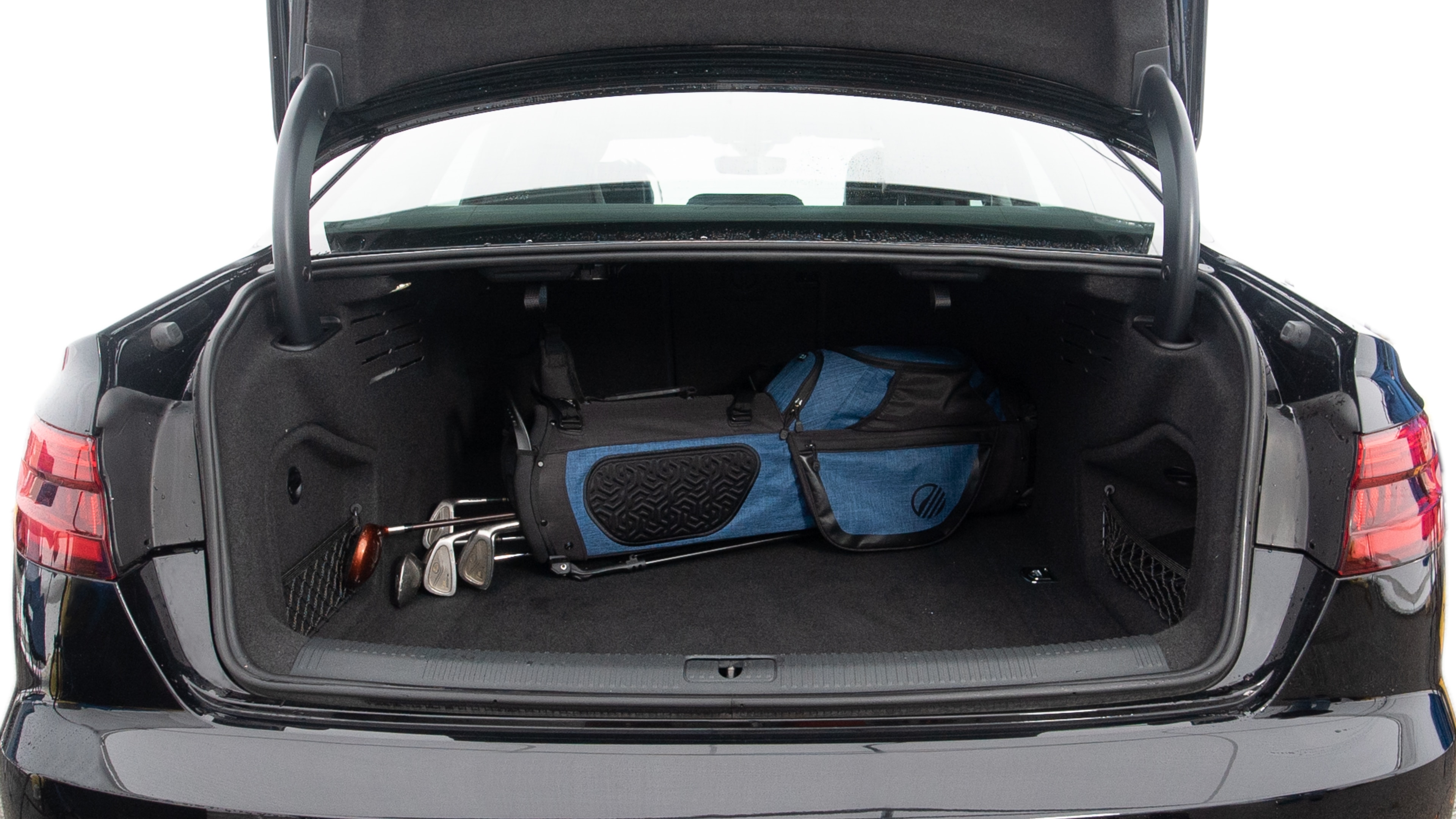 The trunk lid is open showing full view of the trunk. A baby stroller, two grocery carriers, one camping chairs in the carrying bag, and a set of golf clubs are placed inside.