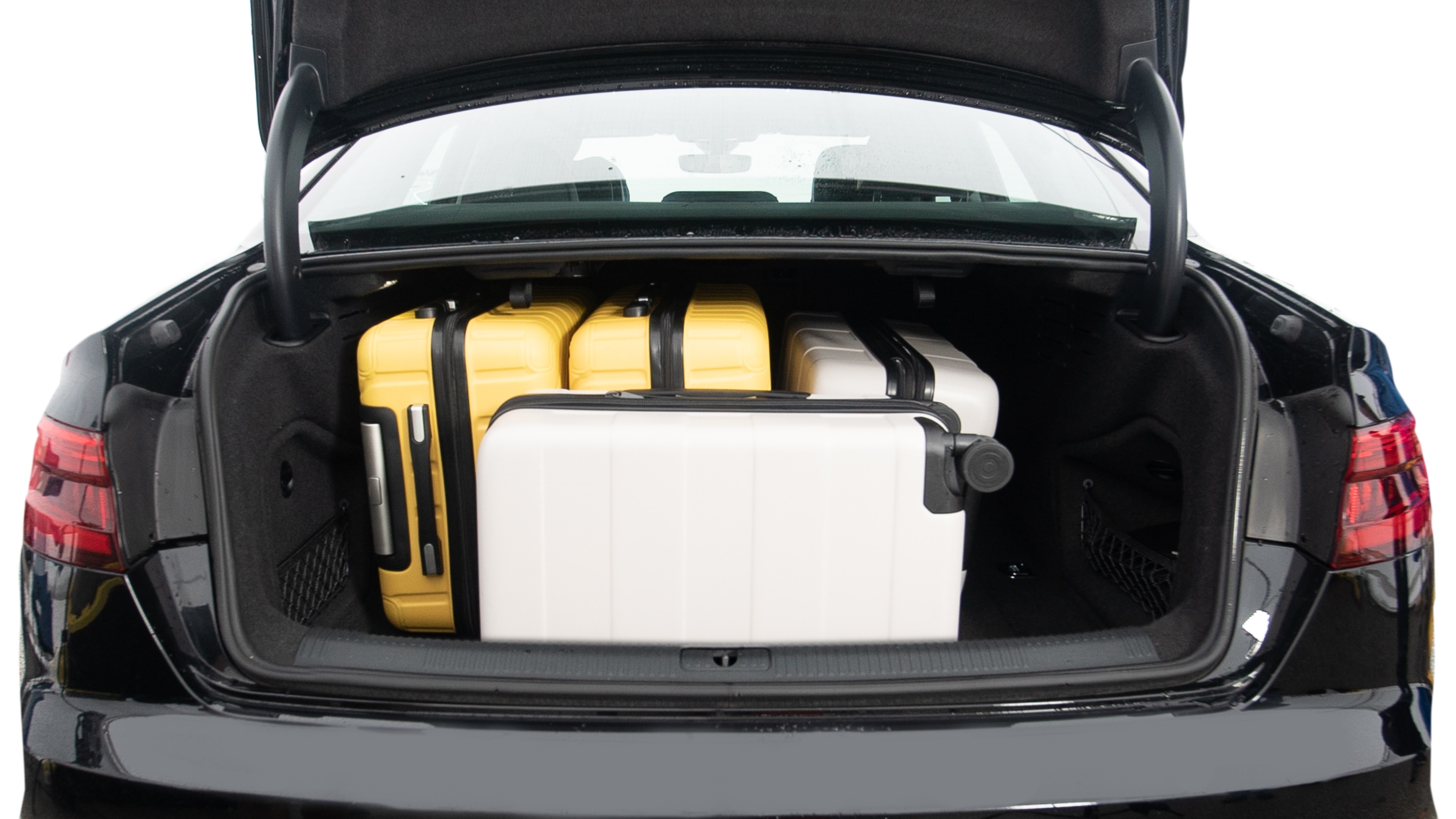 The trunk lid is open, showing full view of the trunk space. Two large and two small suitcases are placed inside.