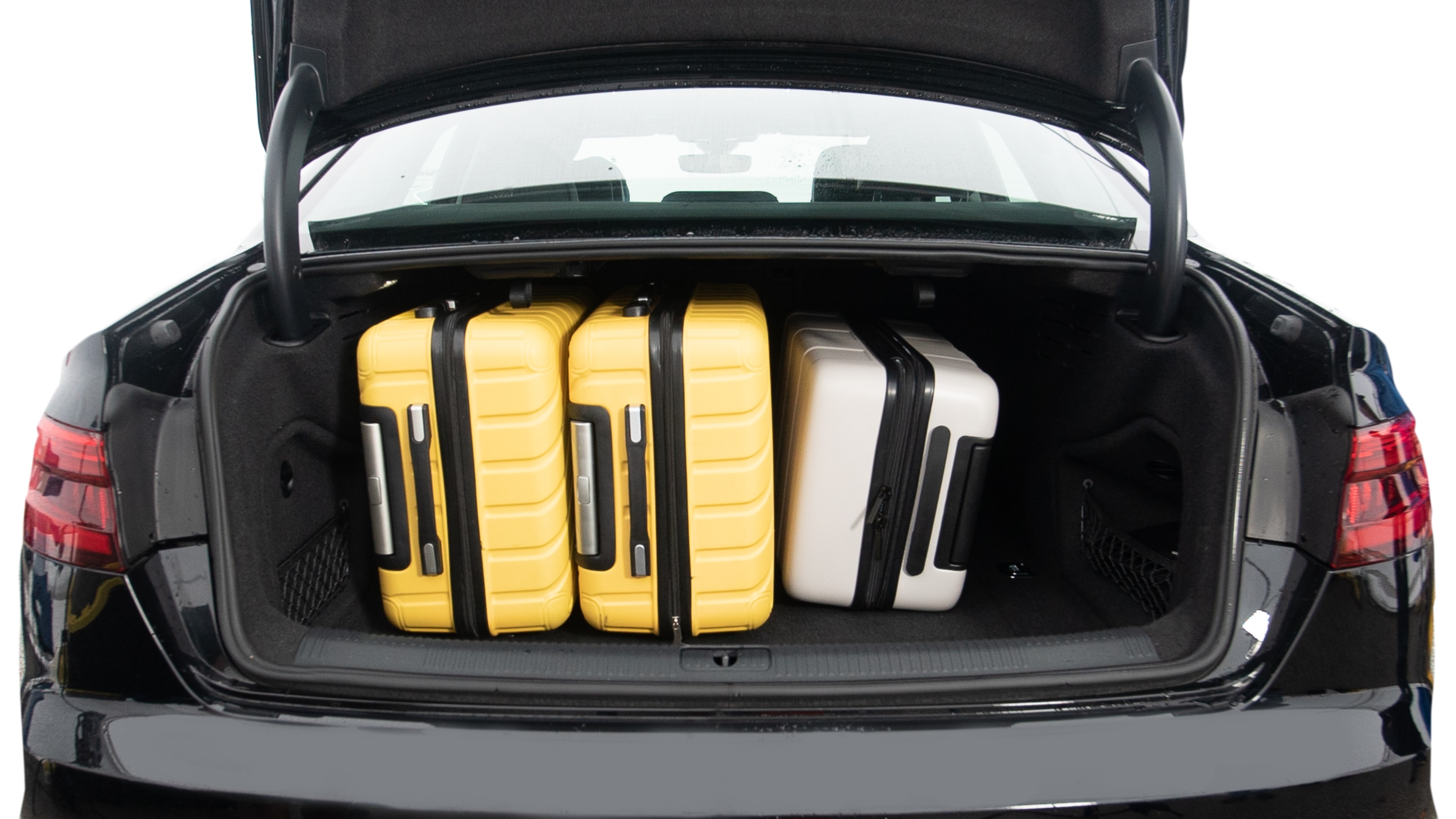 The trunk lid is open, showing full view of the trunk space. Two large and two small suitcases are placed inside.