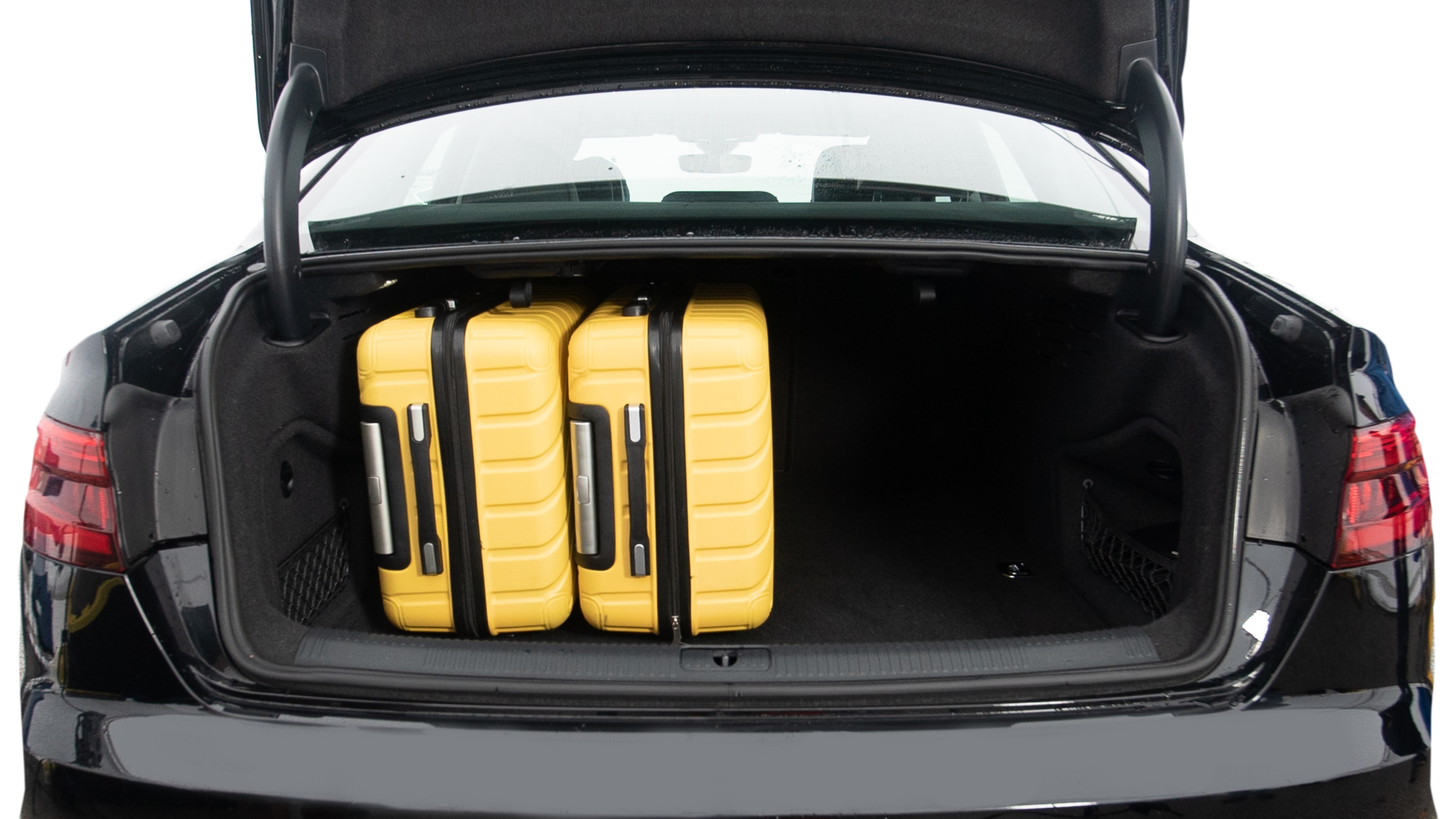 The trunk lid is open, showing full view of the trunk space. Two large and two small suitcases are placed inside.