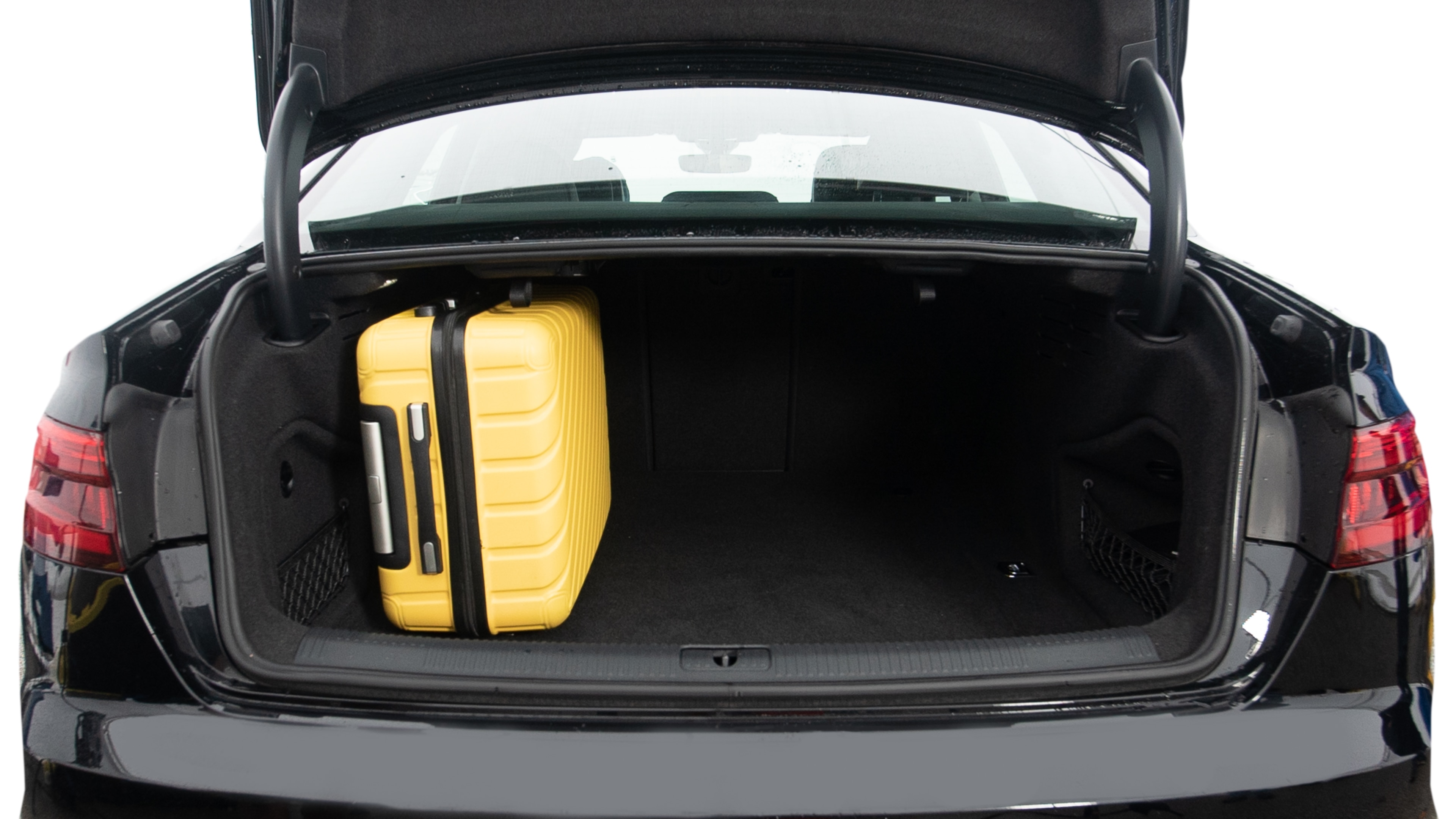 The trunk lid is open, showing full view of the trunk space. Two large and two small suitcases are placed inside.