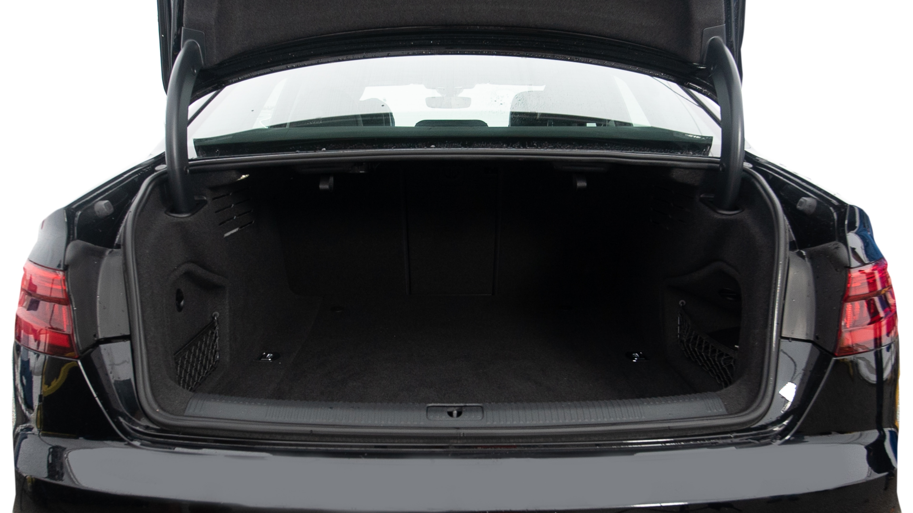 The trunk lid is open, showing full view of the trunk space. Two large and two small suitcases are placed inside.