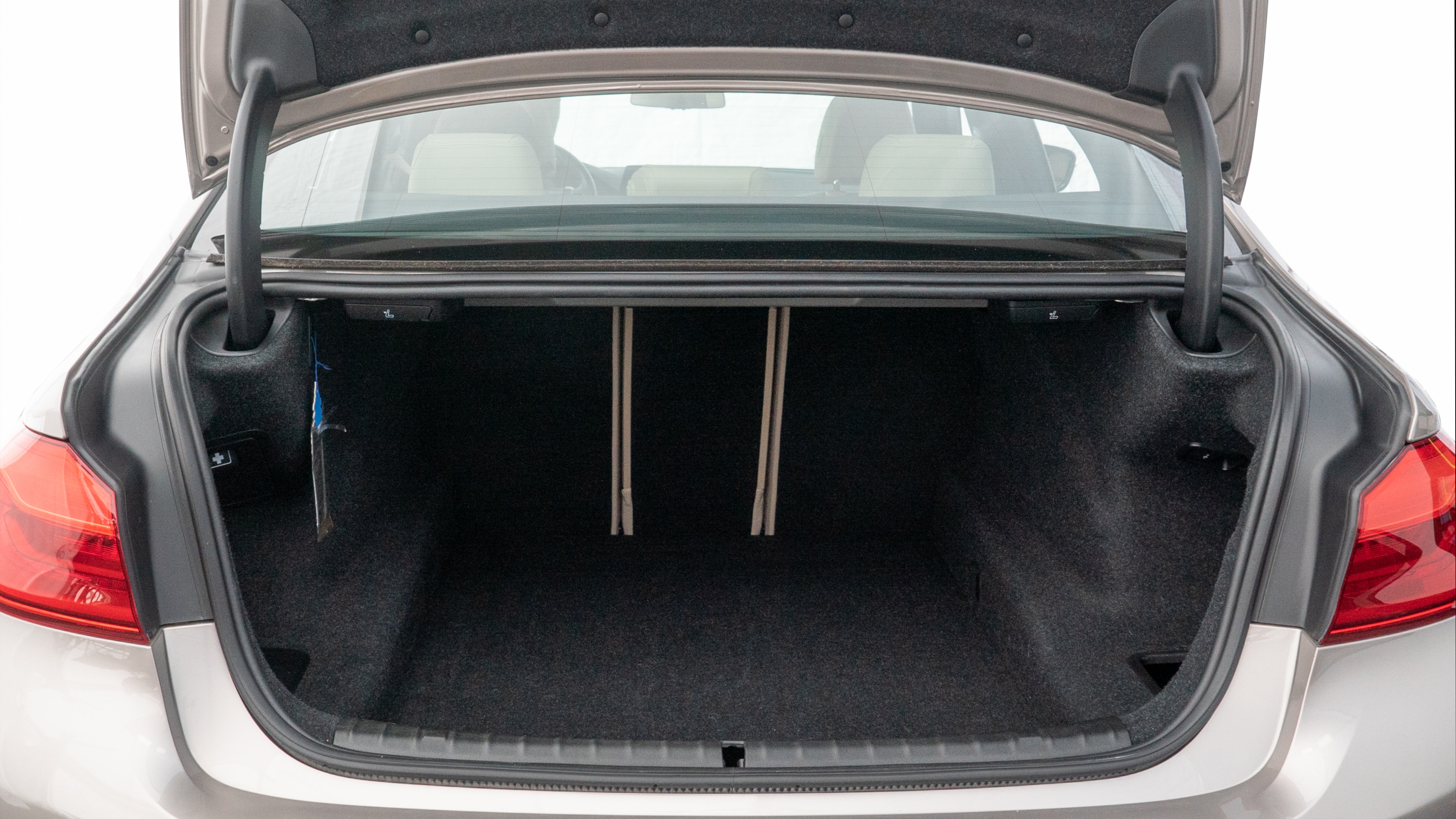The trunk lid is open, showing full view of the trunk space. Two medium and two small suitcases are placed inside.