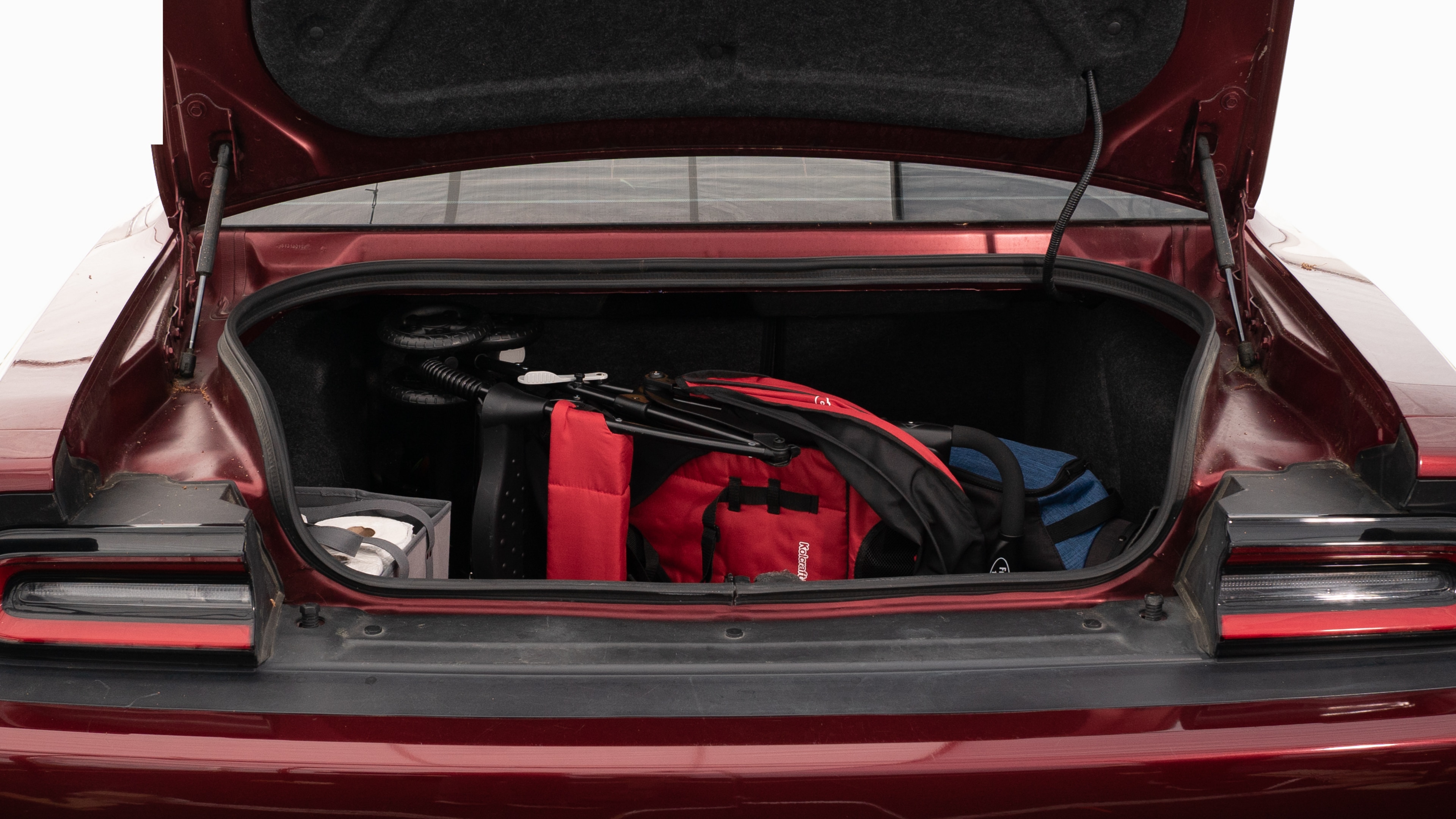 The trunk lid is open showing full view of the trunk. A baby stroller, four grocery carriers, a yoga mat, and a set of golf clubs are placed inside