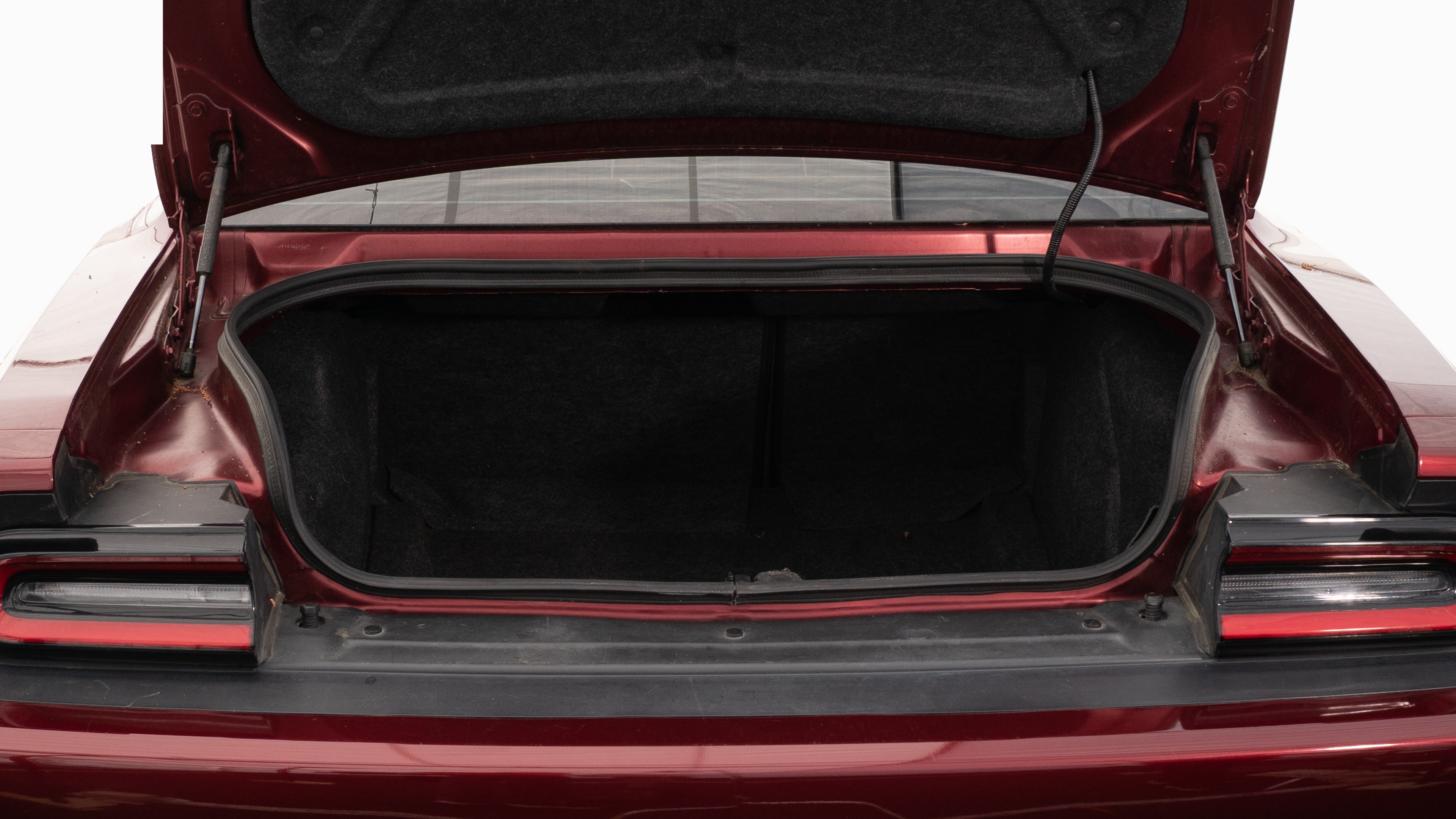 The trunk lid is open showing full view of the trunk. A baby stroller, four grocery carriers, a yoga mat, and a set of golf clubs are placed inside