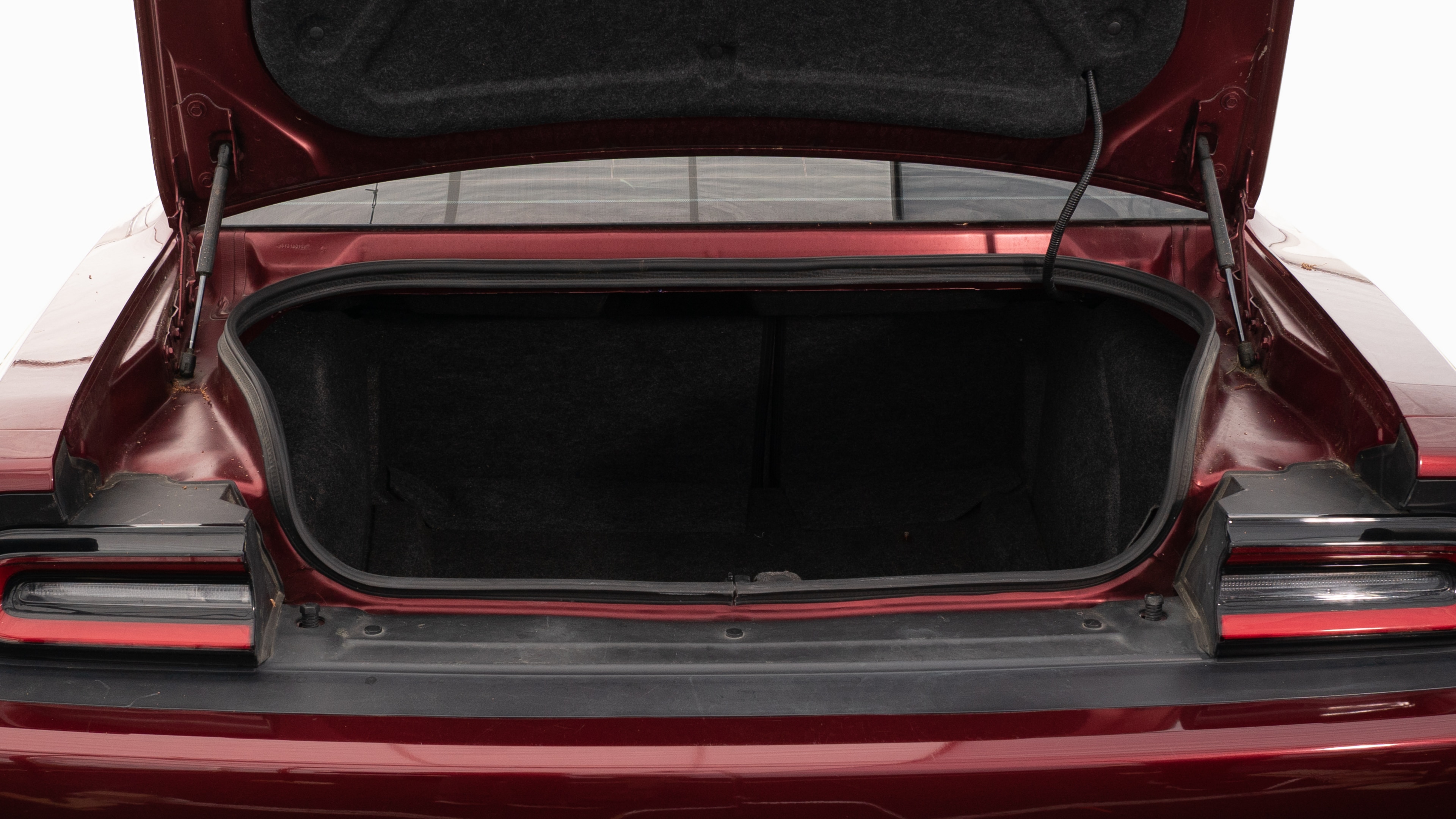 The trunk lid is open, showing full view of the trunk space. Two large and two small suitcases are placed on their sides.